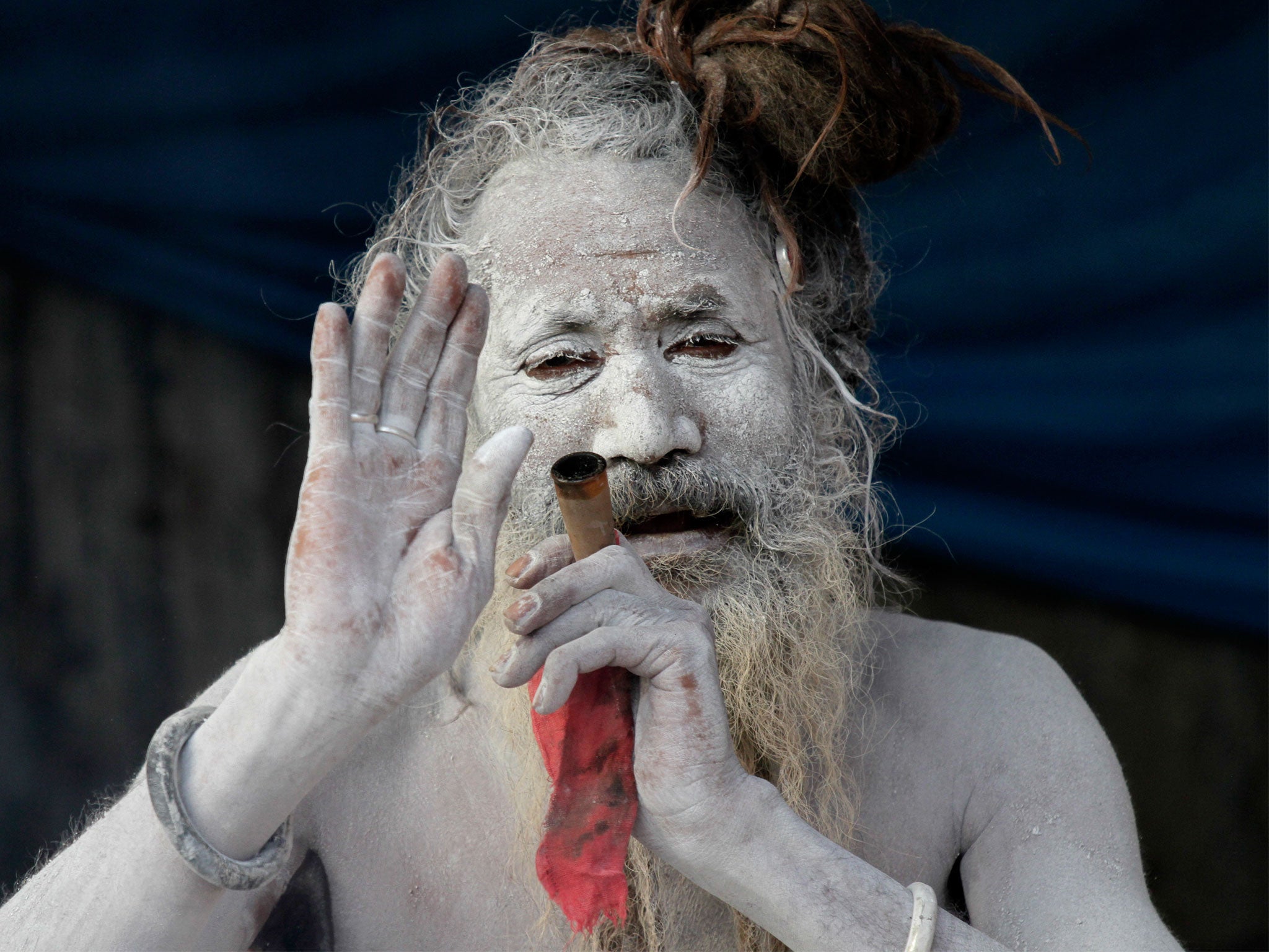 A sadhu, or a Hindu holy man, blesses a devotee as he smokes marijuana at a transit camp on the way to Gangasagar