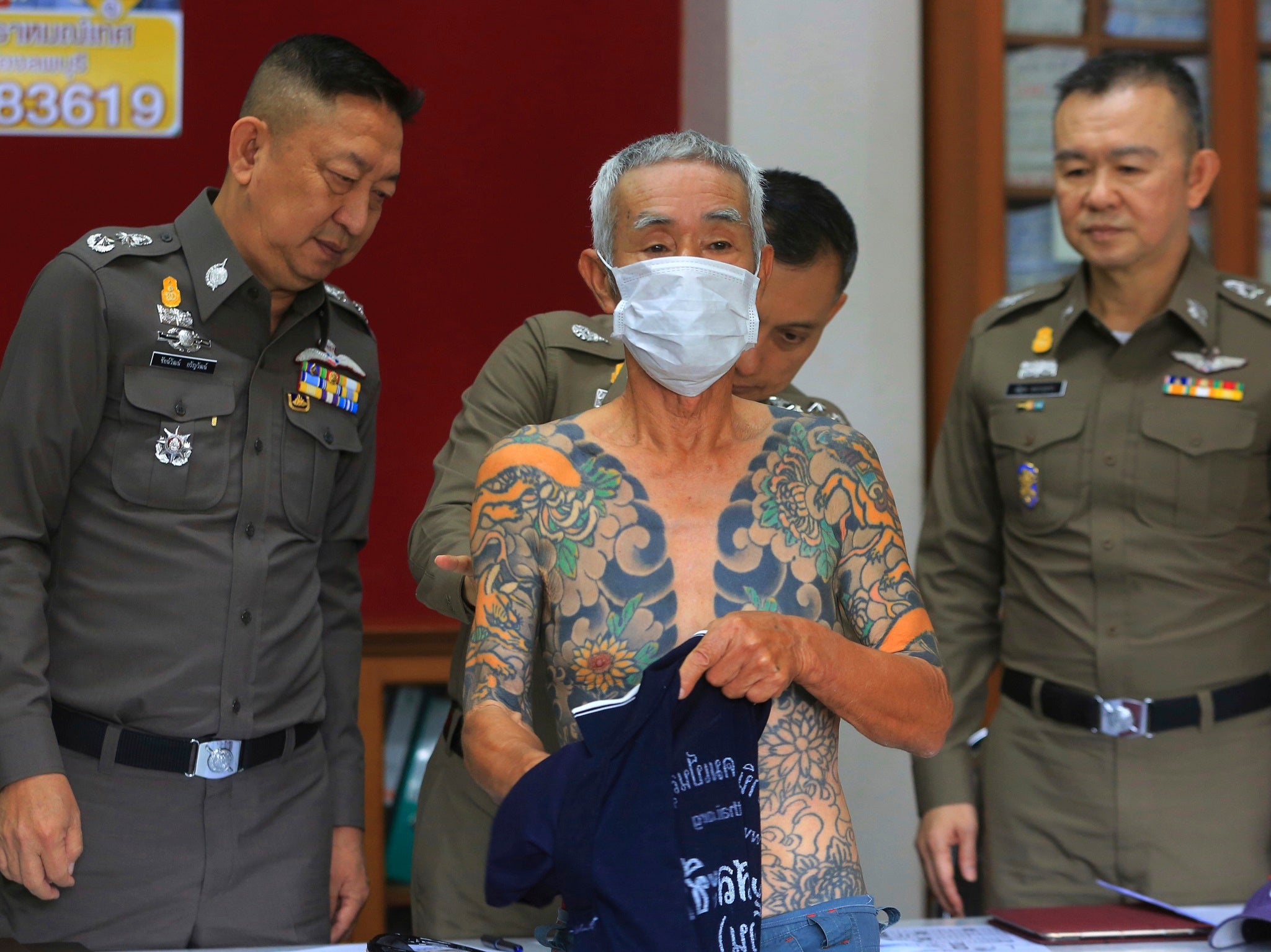 Japanese gang member Shigeharu Shirai displays his tattoos at a police station in central Thailand