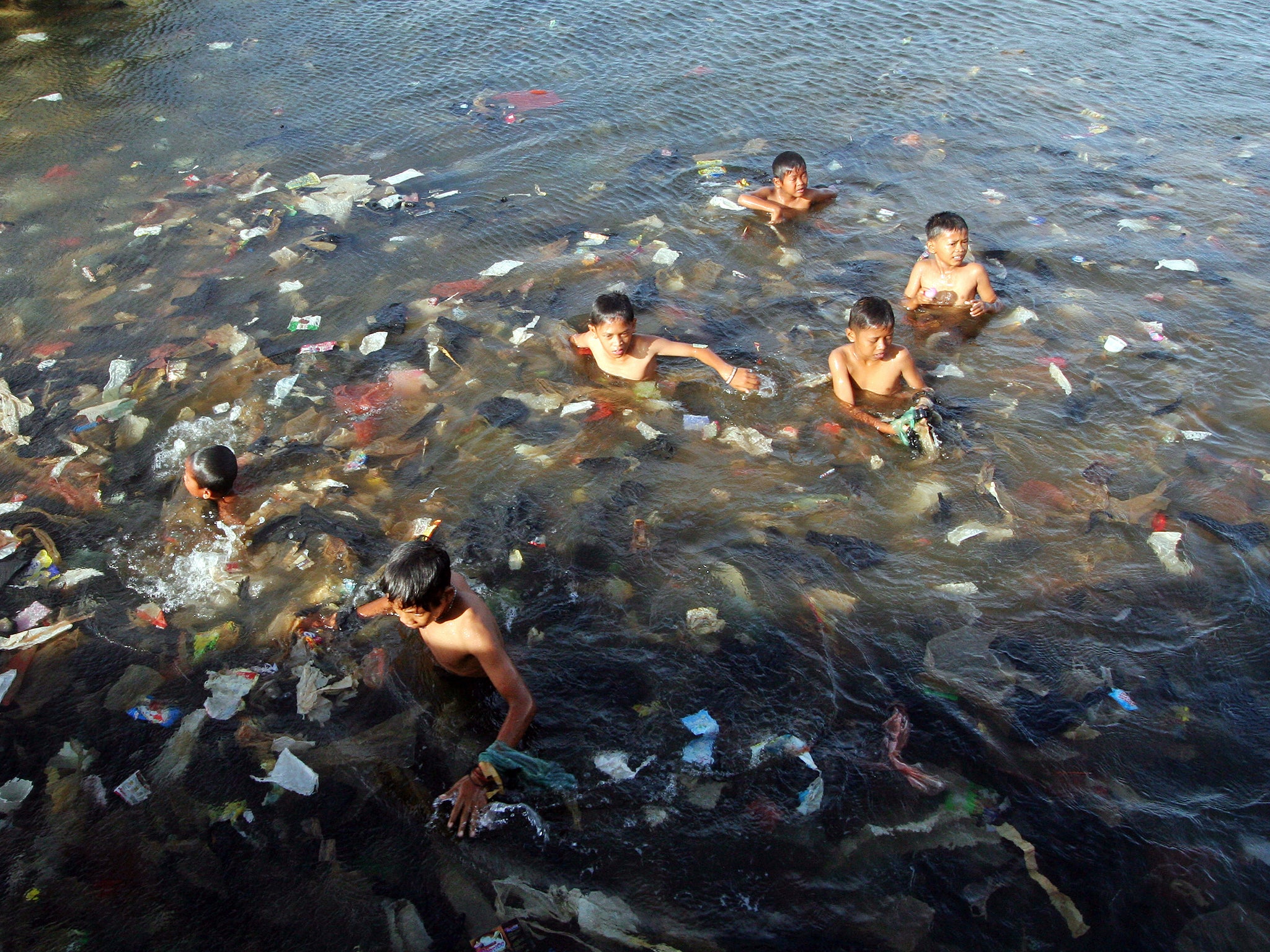 Children swim in the sea full of rubbish in Indonesia (Getty )