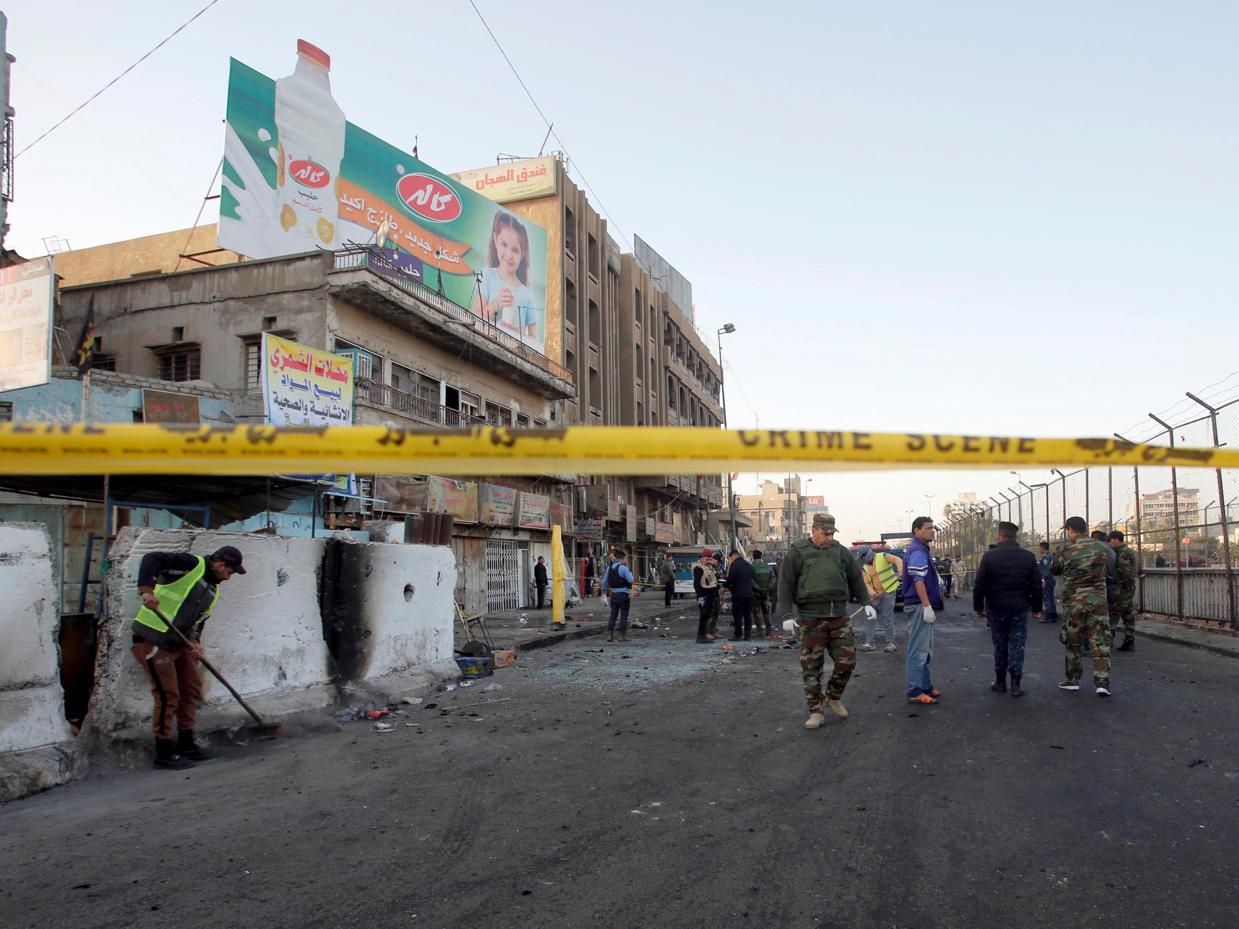 Iraqi security forces inspect the site of the double bombing in Baghdad on Monday