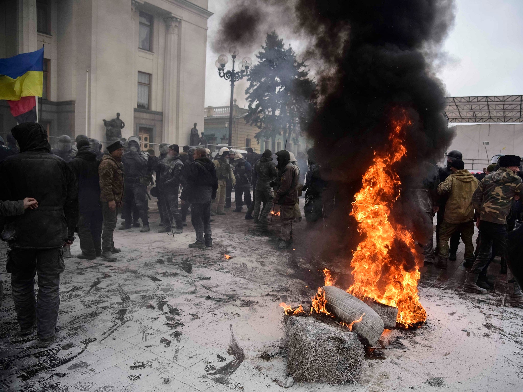 Protesters burn tyres near the Parliament building as riot policemen gather at a camp of supporters of Ukrainian opposition figure and Georgian former President Mikheil Saakashvili