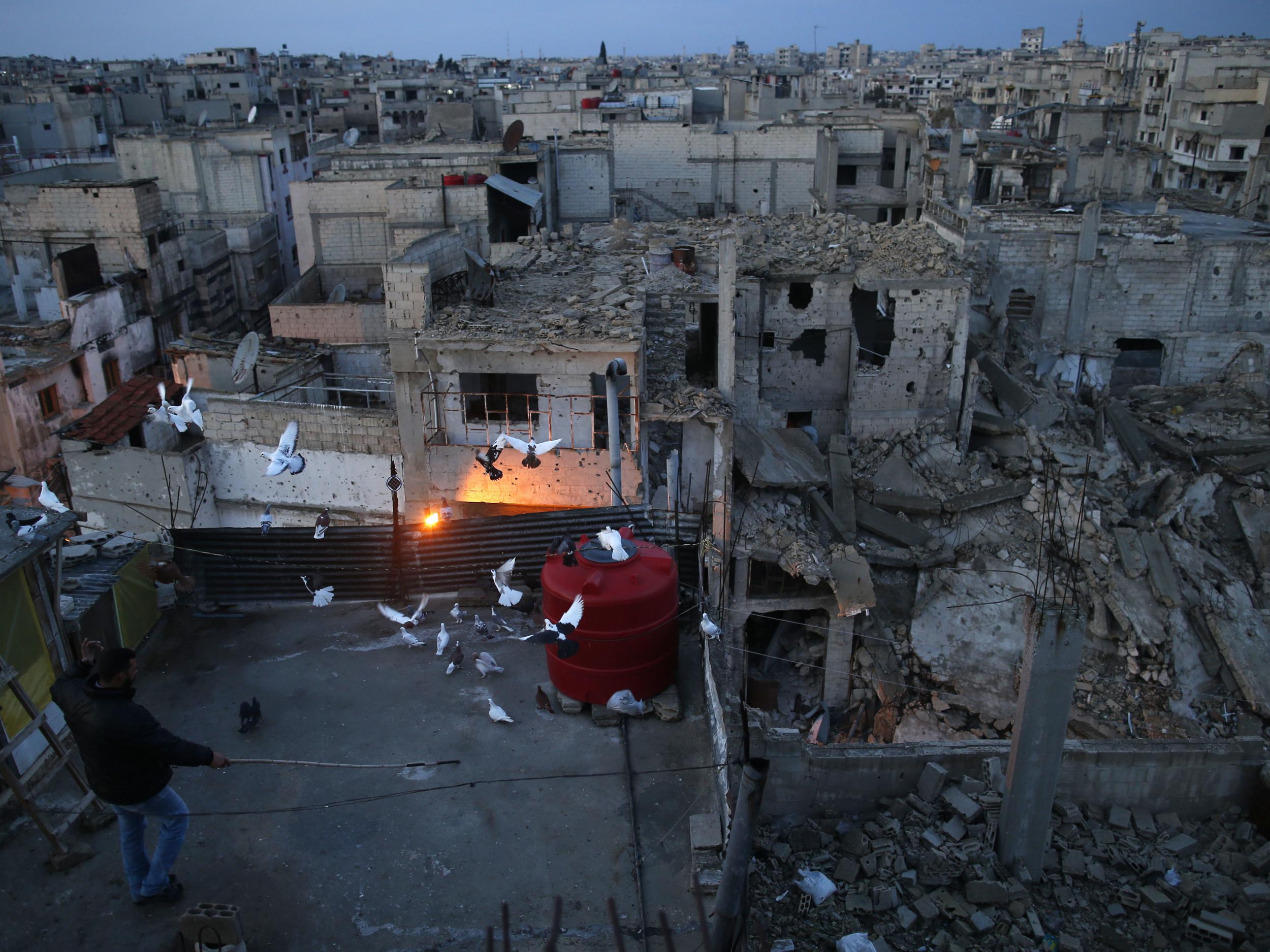 A pigeon-keeper watches his birds fly from the roof of his home in the war-damaged Bab Dreib neighborhood the old city in Homs