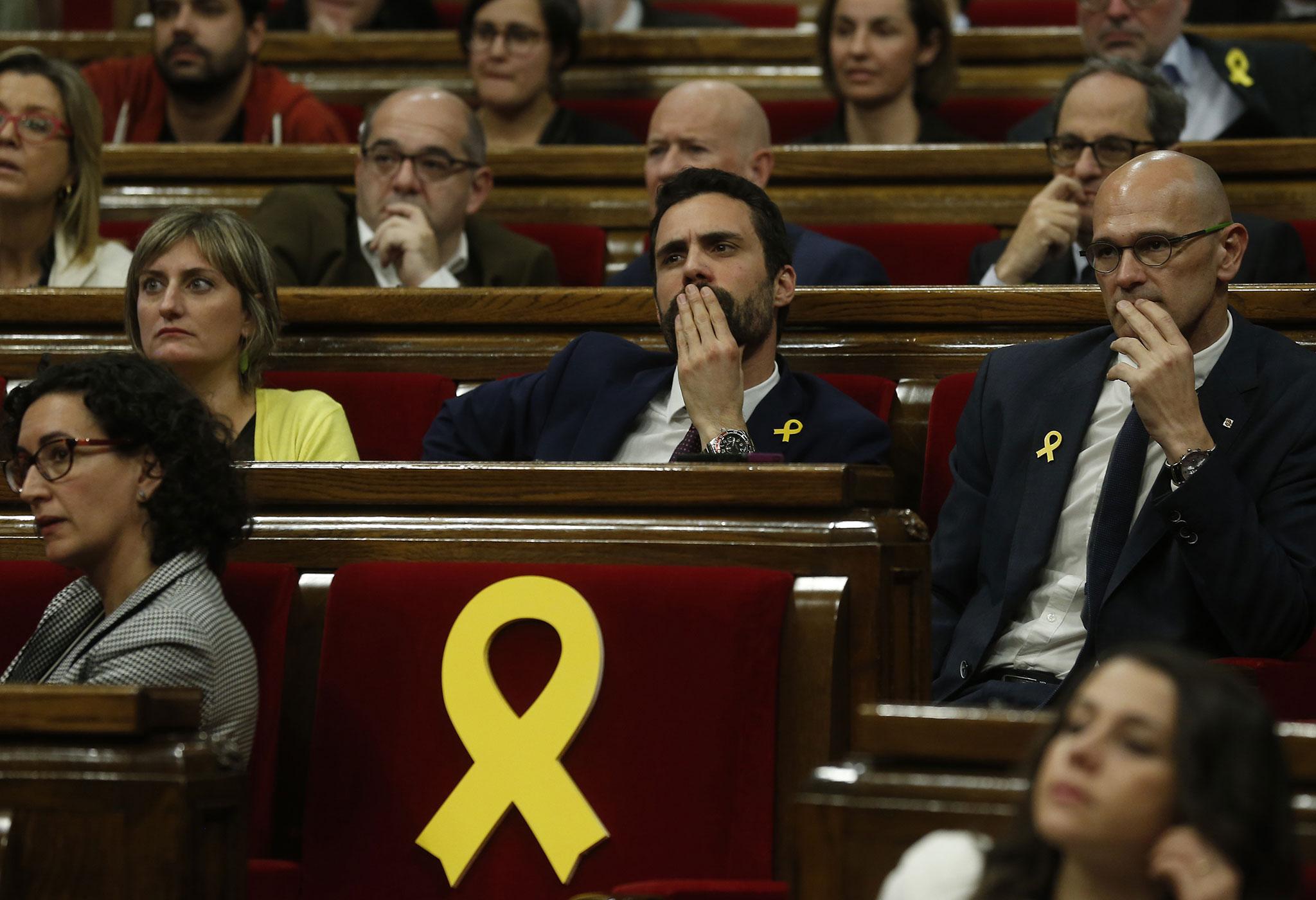 Yellow ribbons marked the seats of Catalan parliamentarians who could not attend the opening session because they are in jail in Madrid