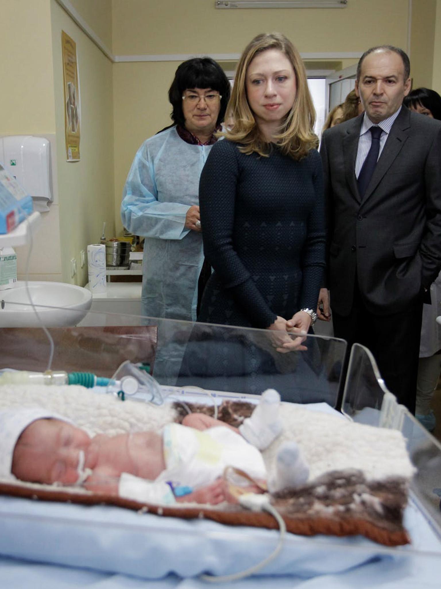 Chelsea Clinton, centre, and Ukrainian billionaire Victor Pinchuk look at a three-week-old baby during a 2012 visit to a neonatal centre in Kiev backed by donations from Pinchuk