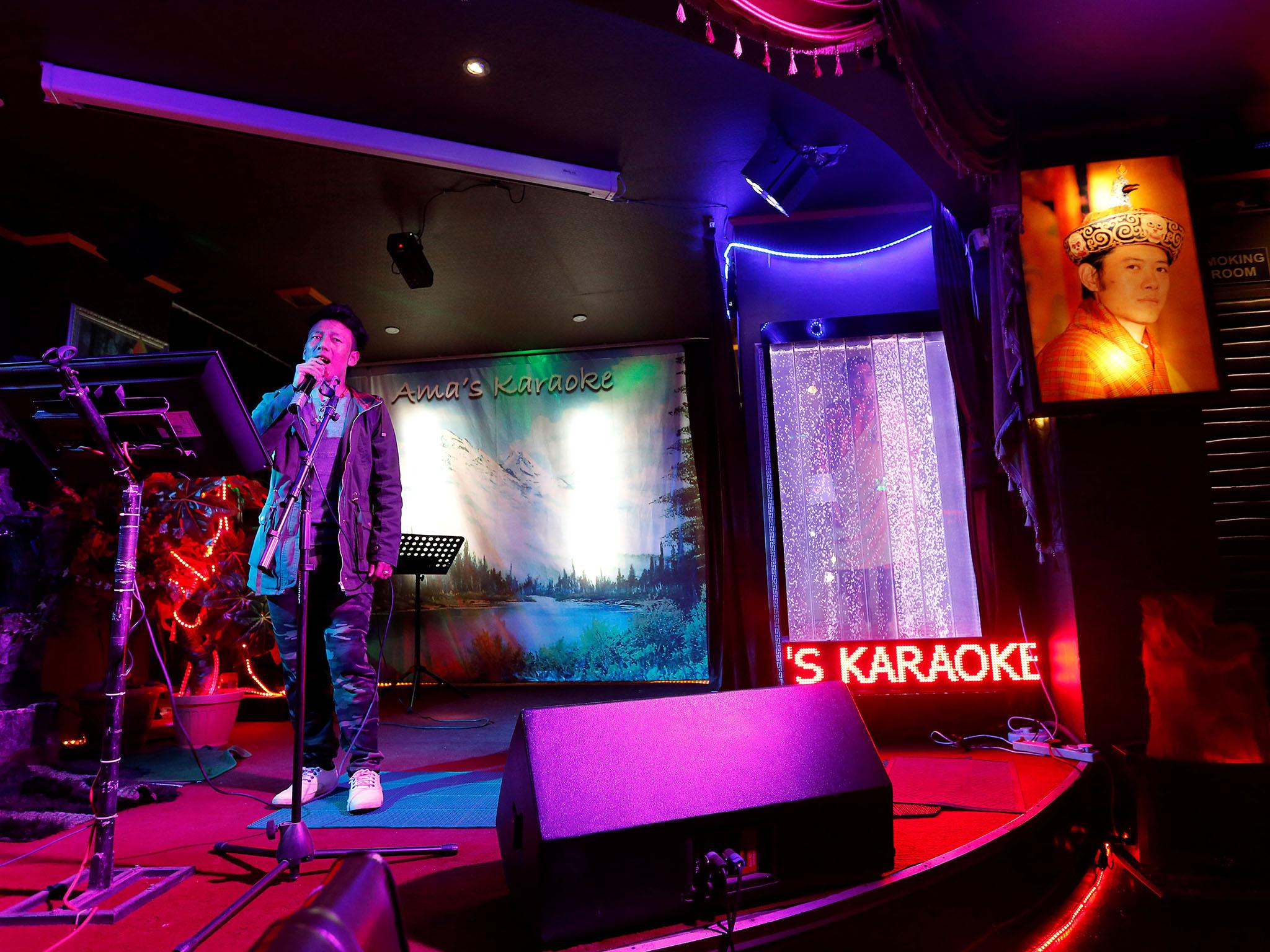 A man sings in a karaoke bar beside a portrait of King Jigme Khesar Namgyel Wangchuck in the capital city of Thimphu