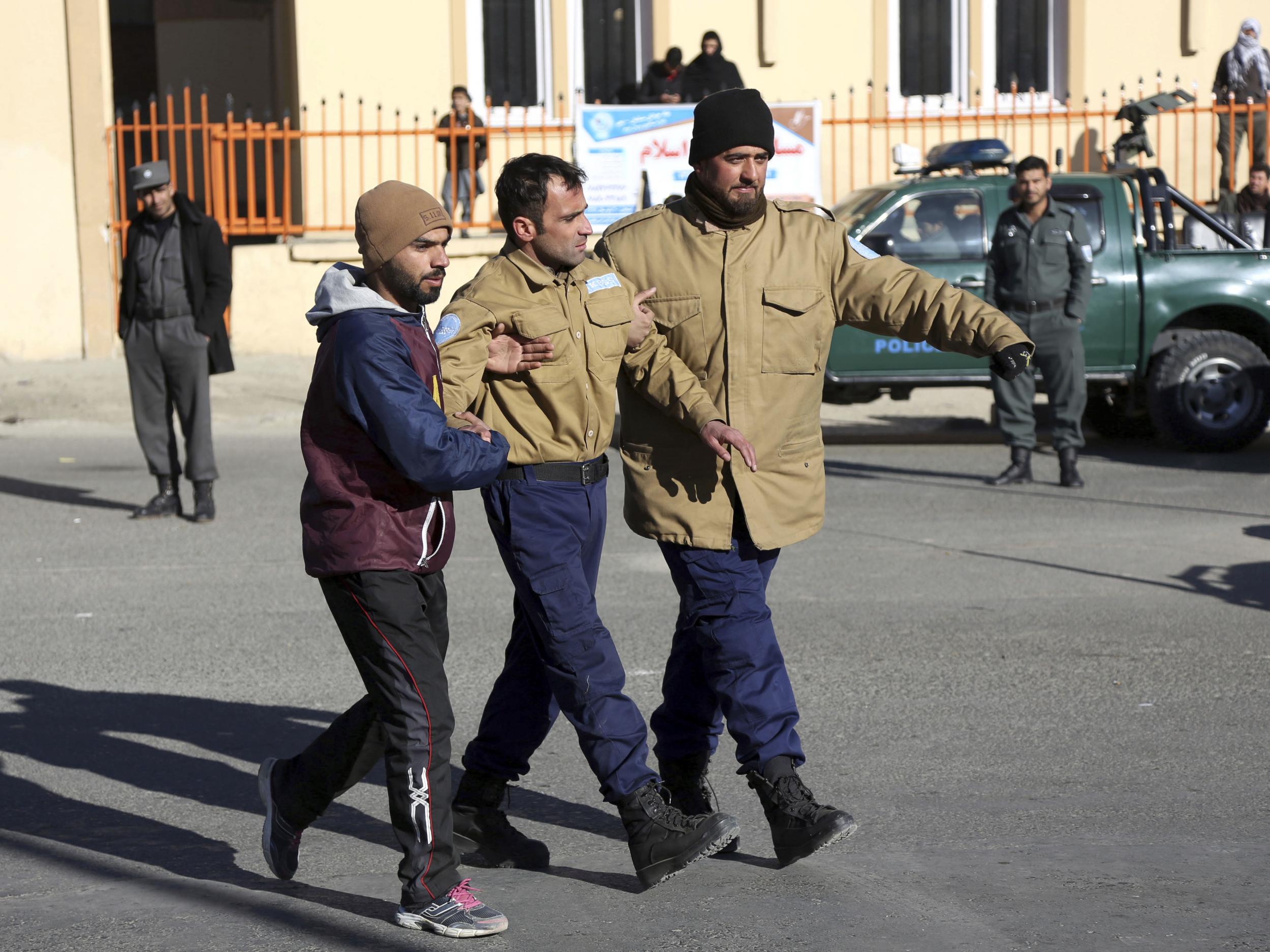 Afghan security personnel escort a man rescued from the Intercontinental Hotel after the attack in Kabul