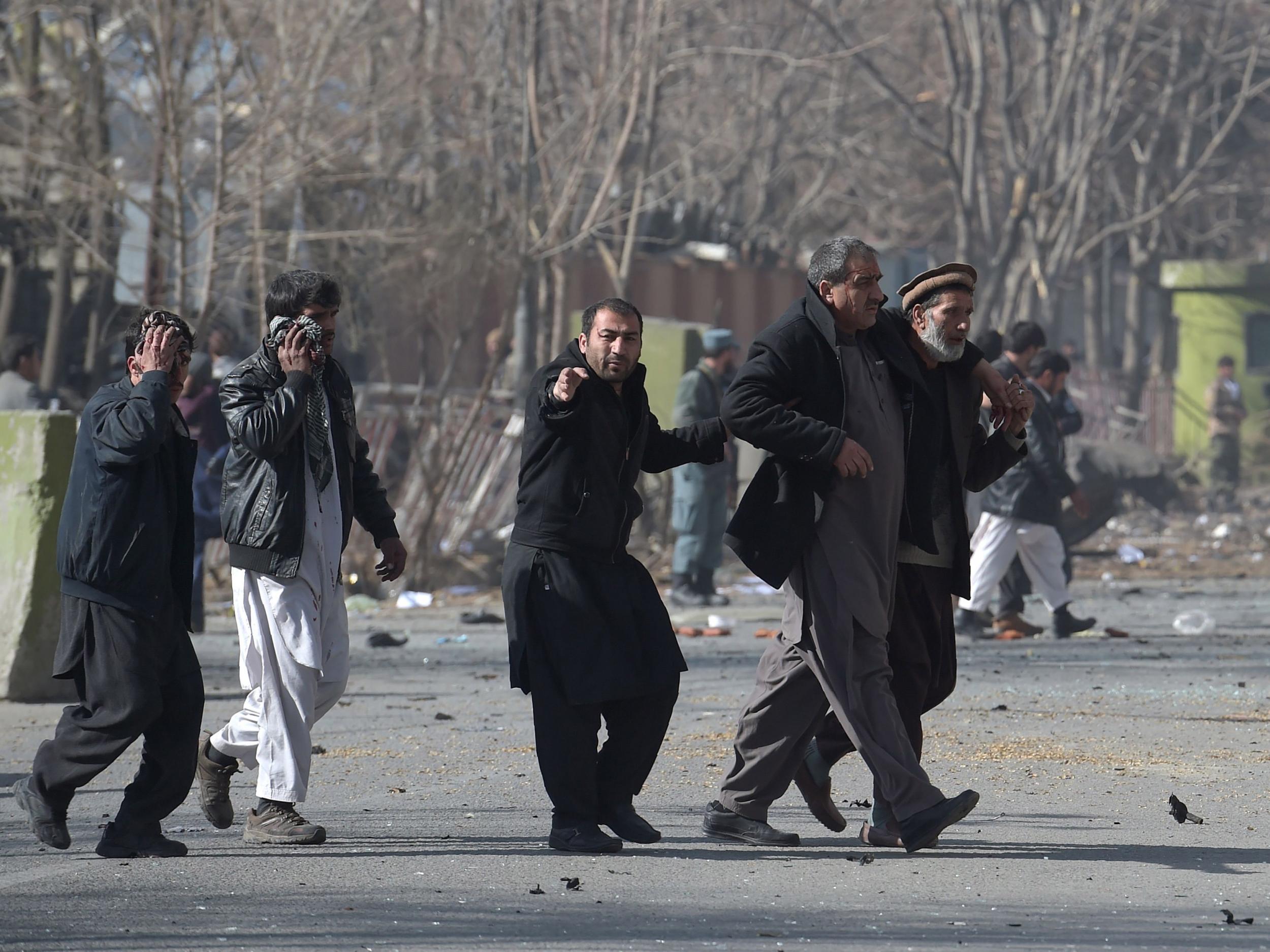 Afghan volunteers help an injured men at the scene of a car bomb exploded in front of the old Ministry of Interior building in Kabul on 27 January 2018