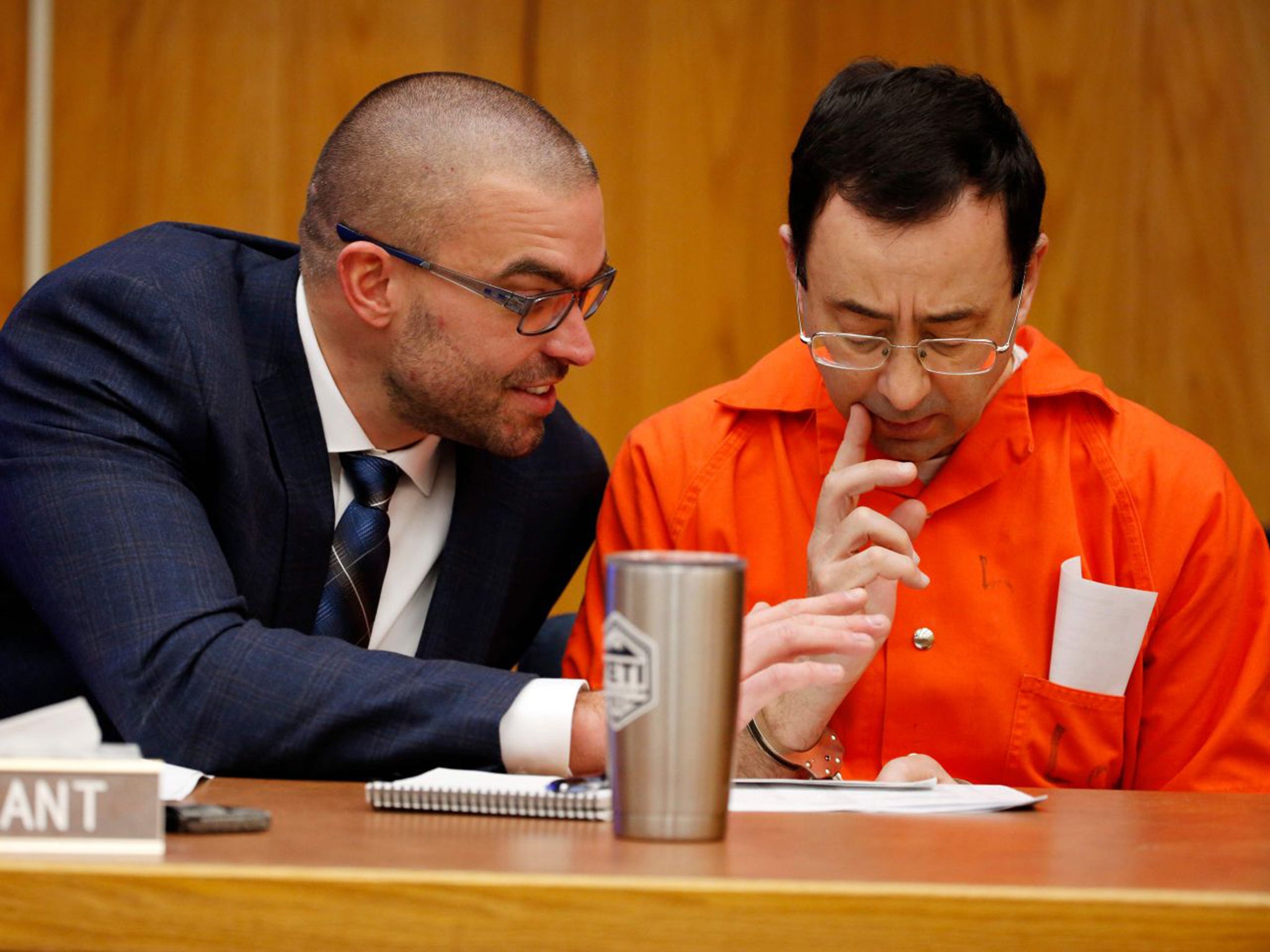 Larry Nassar talks to his defence attorney Matt Newberg (left) in court yesterday