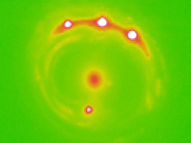 The gravitational lens RX J1131-1231 galaxy can be seen at the centre, with four lensed background quasars