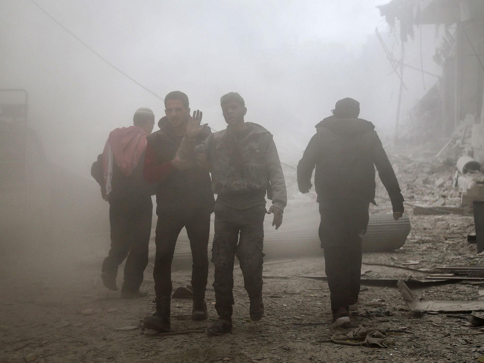 An injured man walks through the dust after a reported air strike in the rebel-held town of Saqba, in the besieged Eastern Ghouta region on the outskirts of the capital Damascus