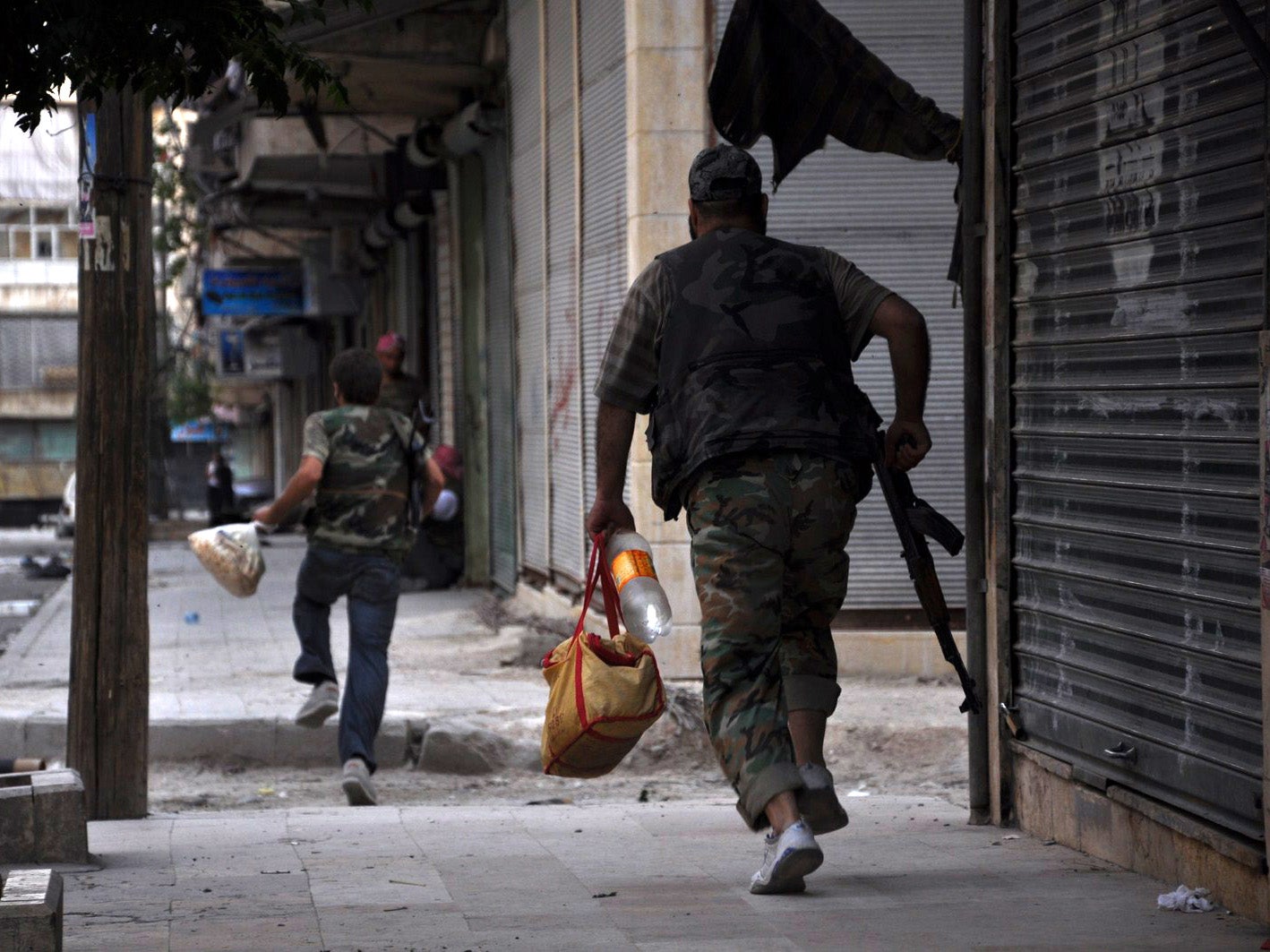 Fighters carrying food supplies run for cover in the Syrian city of Aleppo in July 2012 ahead of violent clashes between government forces and rebels