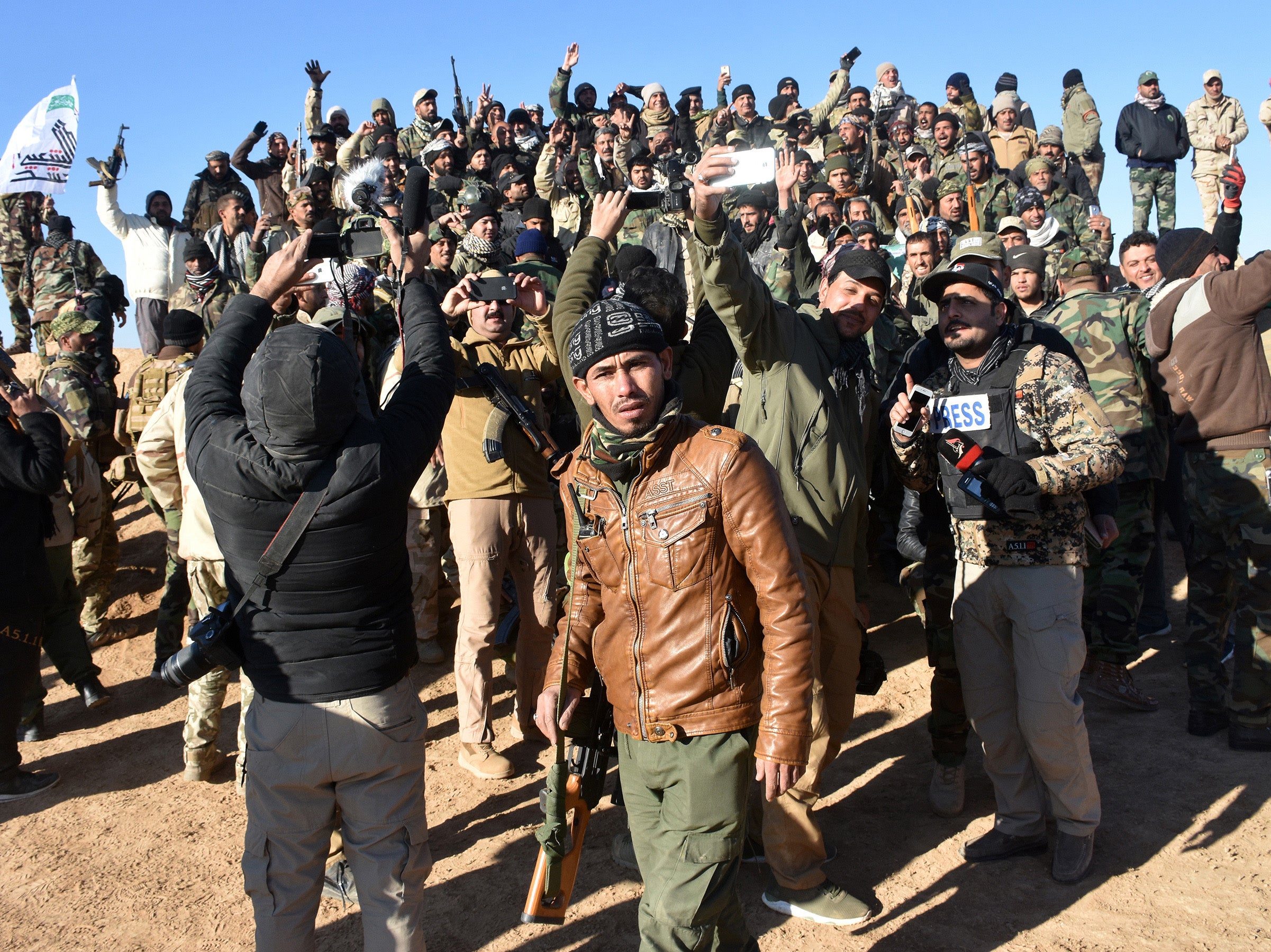 Members of the Hashed al-Shaabi (Popular Mobilisation units) in the Iraqi-Syrian border town of al-Qaim take selfies after the announcement of victory over Isis in December last year