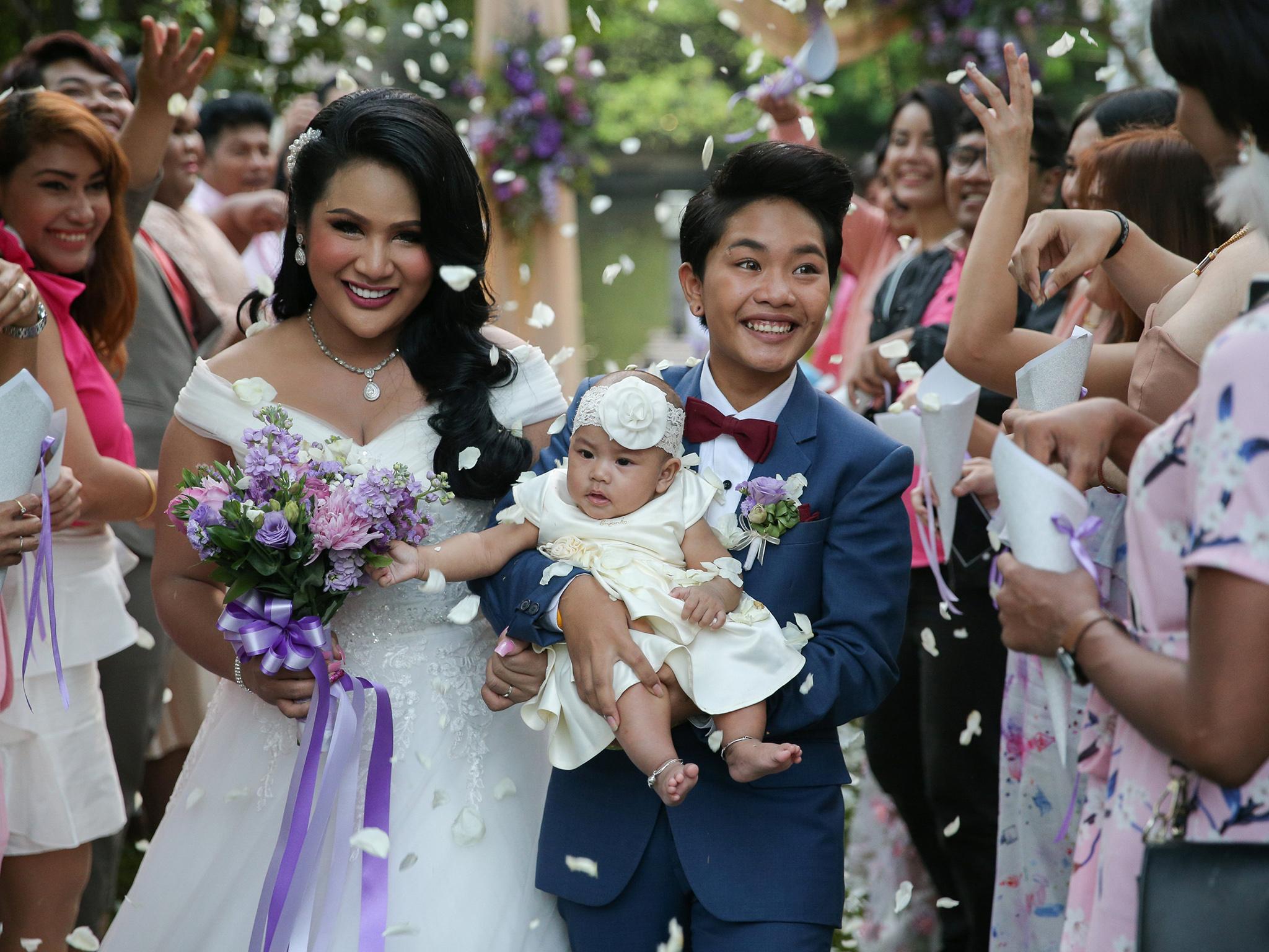 Bride Amornrat Ruamsin (L), 27, who is a transgender, holds up her five-month-old daughter with her groom Pitchaya Kachainrum (R), 16, during their wedding ceremony organised by a local TV show, in Bangkok, Thailand, February 9, 2018. The ceremony is not legally-binding as Pitchaya in under 17, the legal age for marriage in Thailand. The couple plan to officially wed after her birthday. "I've had relationships with men before, but it was not that good and I was heartbroken many times. I met Pitchaya on Facebook and I first sent her a message to introduce myself. We fell in love with each other. After living together for more then a year, we agreed to have a baby. So now we have five-month-old daughter and today we got married as our parents wanted. This is the happiest day of my life," Amornrat said. REUTERS/Athit Perawongmetha      SEARCH "GLOBAL LOVE" FOR THIS STORY. SEARCH "WIDER IMAGE" FOR ALL STORIES.