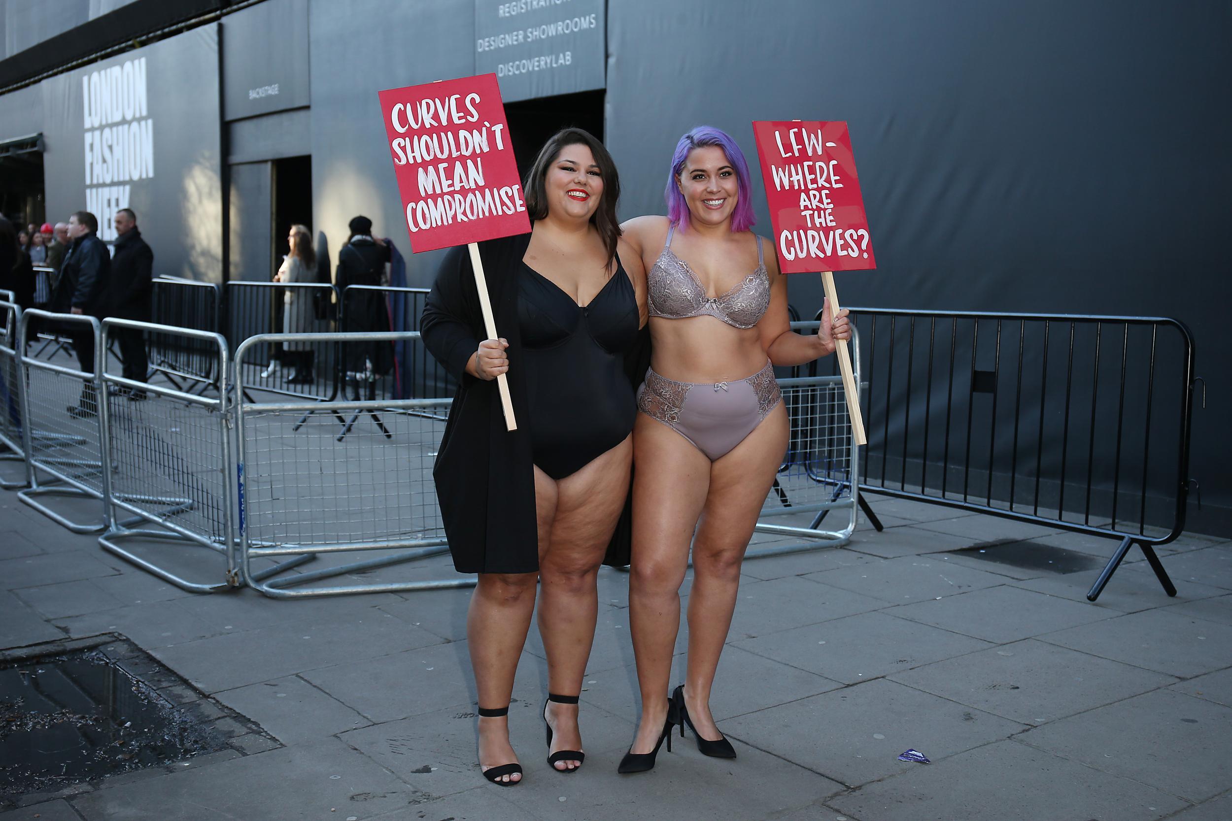 The models held signs questioning why plus-size models are still not shown on the runway