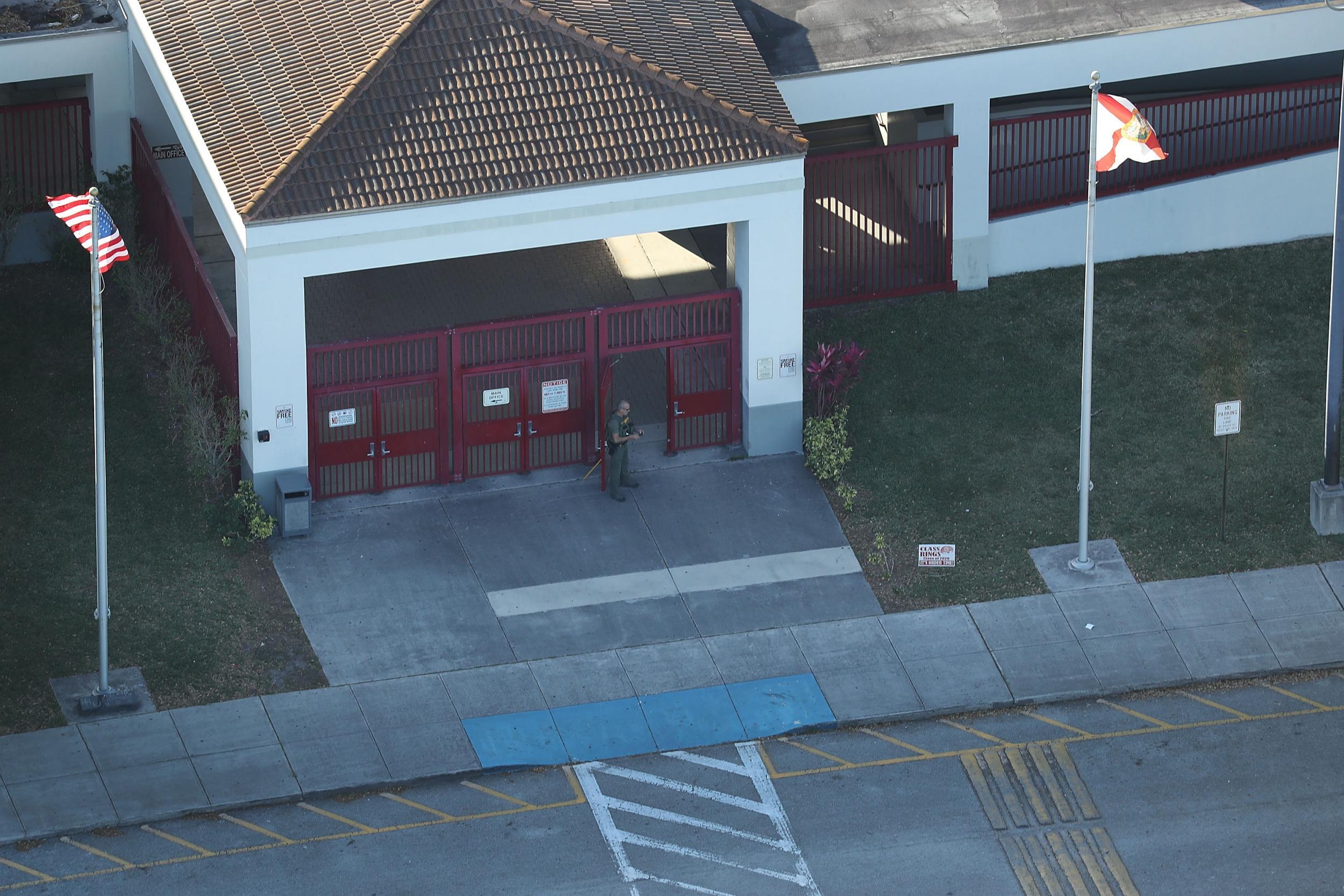 A law enforcement officer stands at the front door of the Marjory Stoneman Douglas High School after a shooting