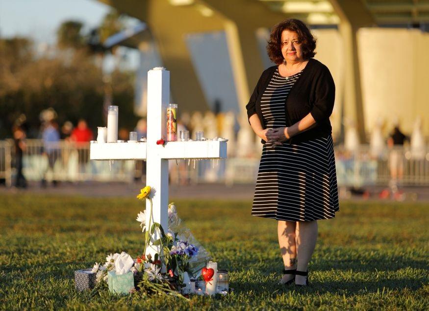 Diana Haneski stands next to a cross erected for the victims of the school shooting in Parkland, Florida