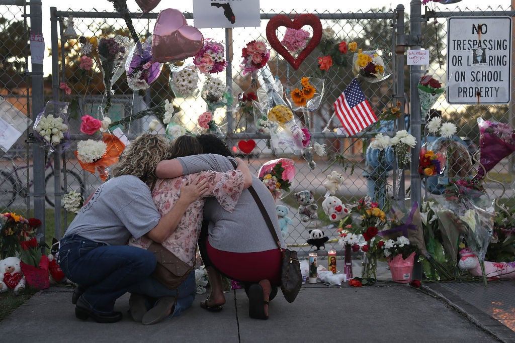 Women comfort each other at a memorial for victims of the Parkland massacre