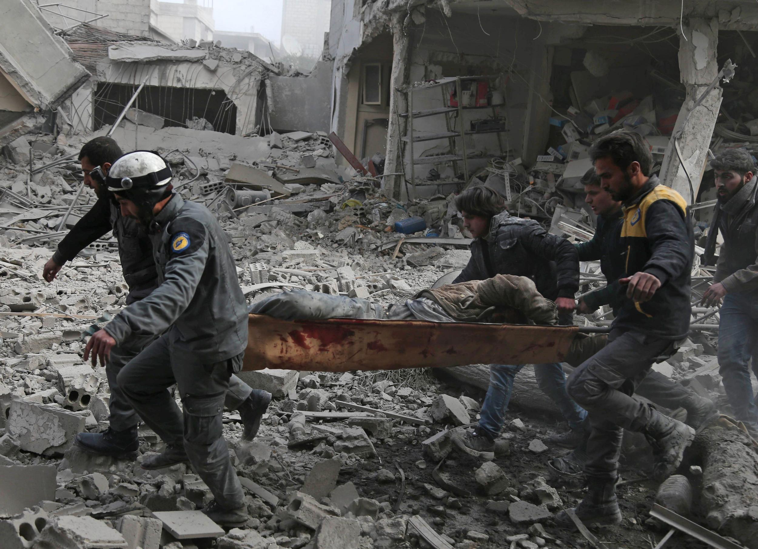 Members of the Syrian Civil Defence, also known as the White Helmets, evacuate an injured civilian on a stretcher from an area hit by a reported regime air strike in the rebel-held town of Saqba, in the besieged Eastern Ghouta region on the outskirts of the capital Damascus