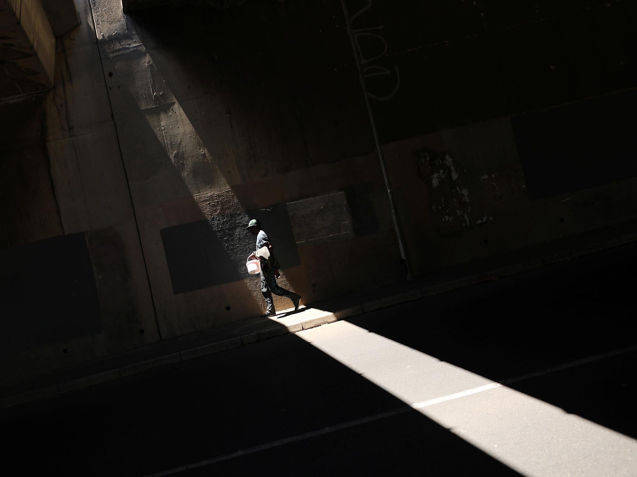 A man carries a bucket used to collect water from a small roadside spring