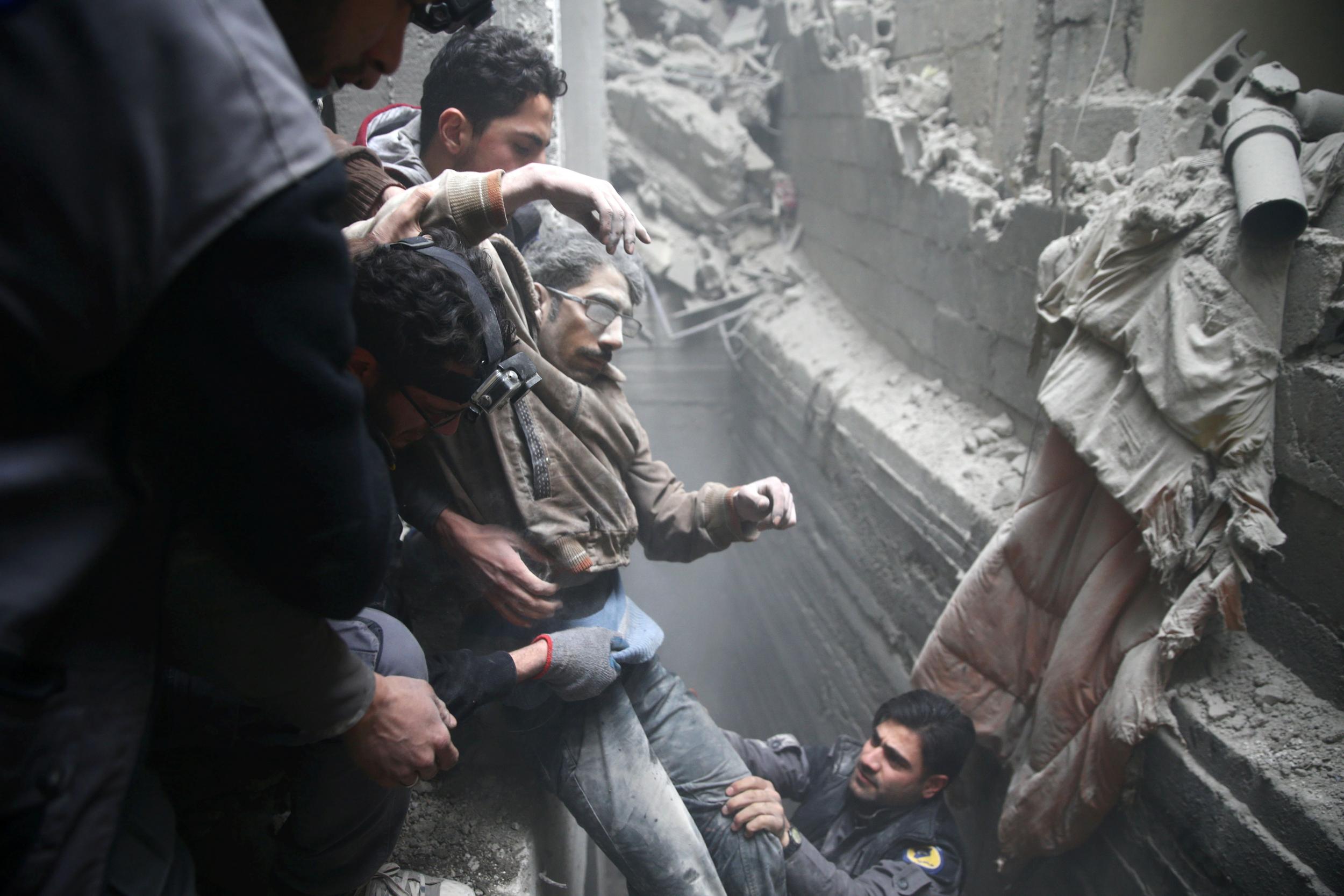 Civil defence rescue workers help a man from a shelter after an air strike in the besieged town of Douma in eastern Ghouta, 22 February 2018