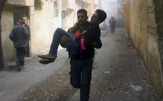 Members of the Syrian Civil Defense group, known as the White Helmets, carry a young man who was wounded during air strikes and shelling by Syrian government forces in Eastern Ghouta