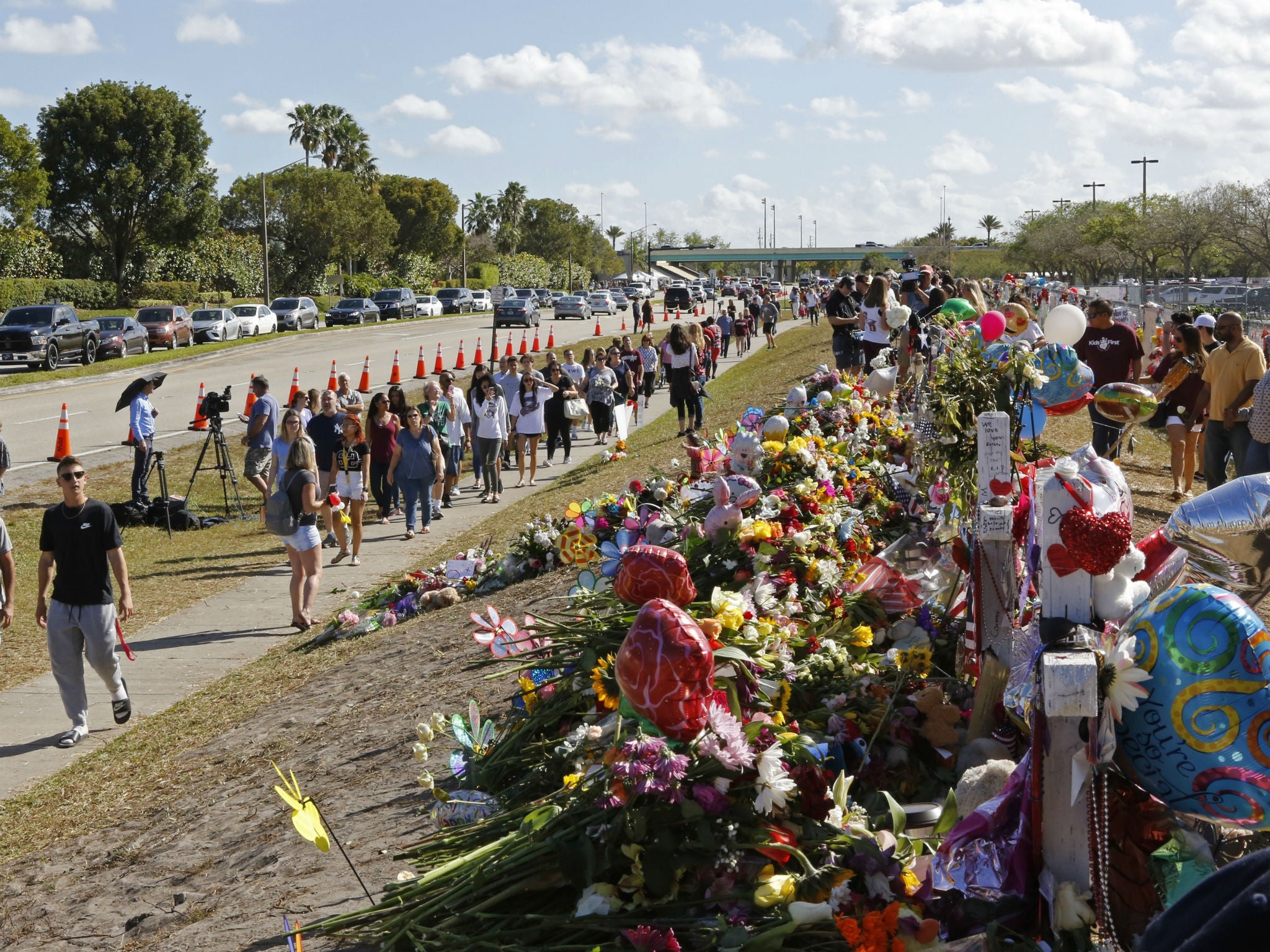 Parents and students walk by the memorial for the victims of the shooting at Marjory Stoneman Douglas High School on the way to open day