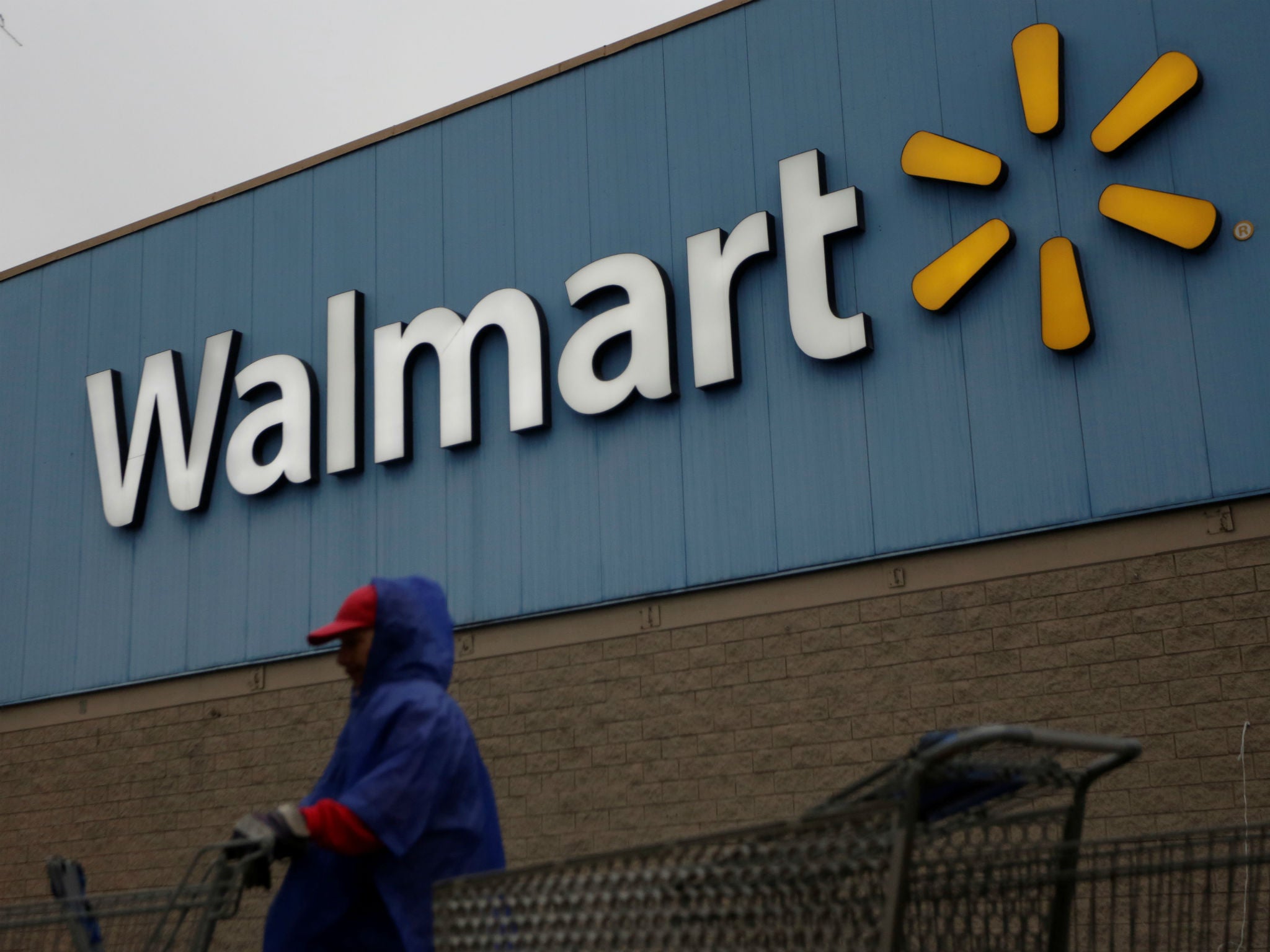 An employee arranges shopping carts in front of a Walmart store