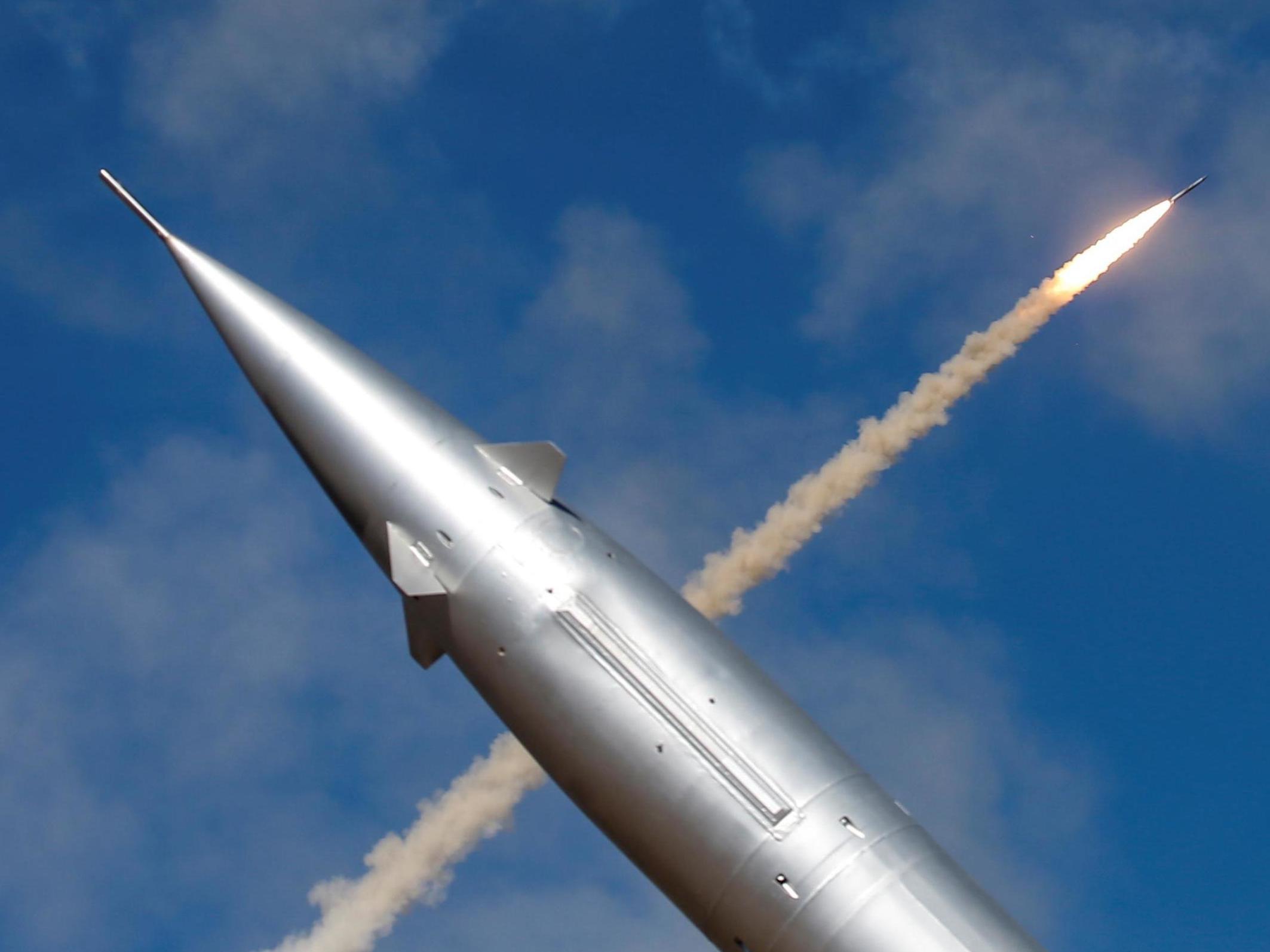 A missile of an anti-aircraft defence mobile missile system is seen in front of a missile launched from S-300 antiaircraft system