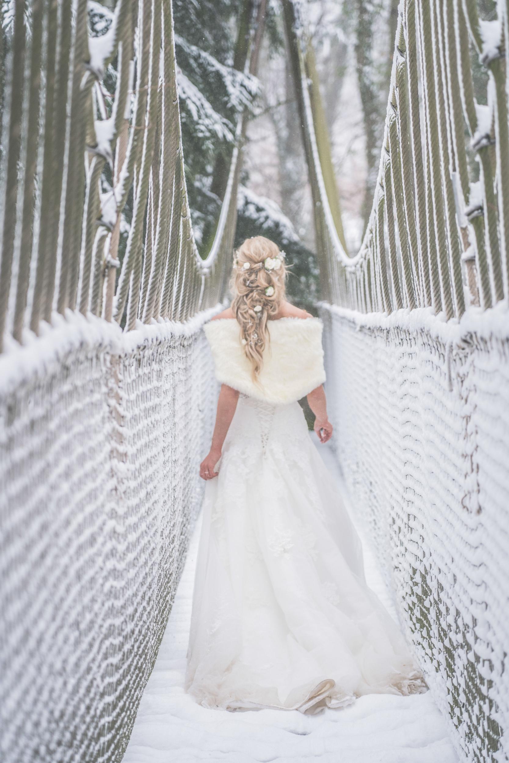 The bride walks across a snowy bridge (Sean Elliott Photography)