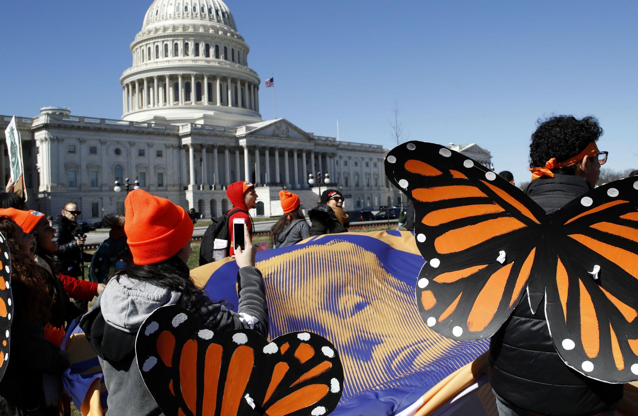 Supporters of the Deferred Action for Childhood Arrivals (DACA) programme hold a tarp with an image of President Donald Trump as they march in support of DACA