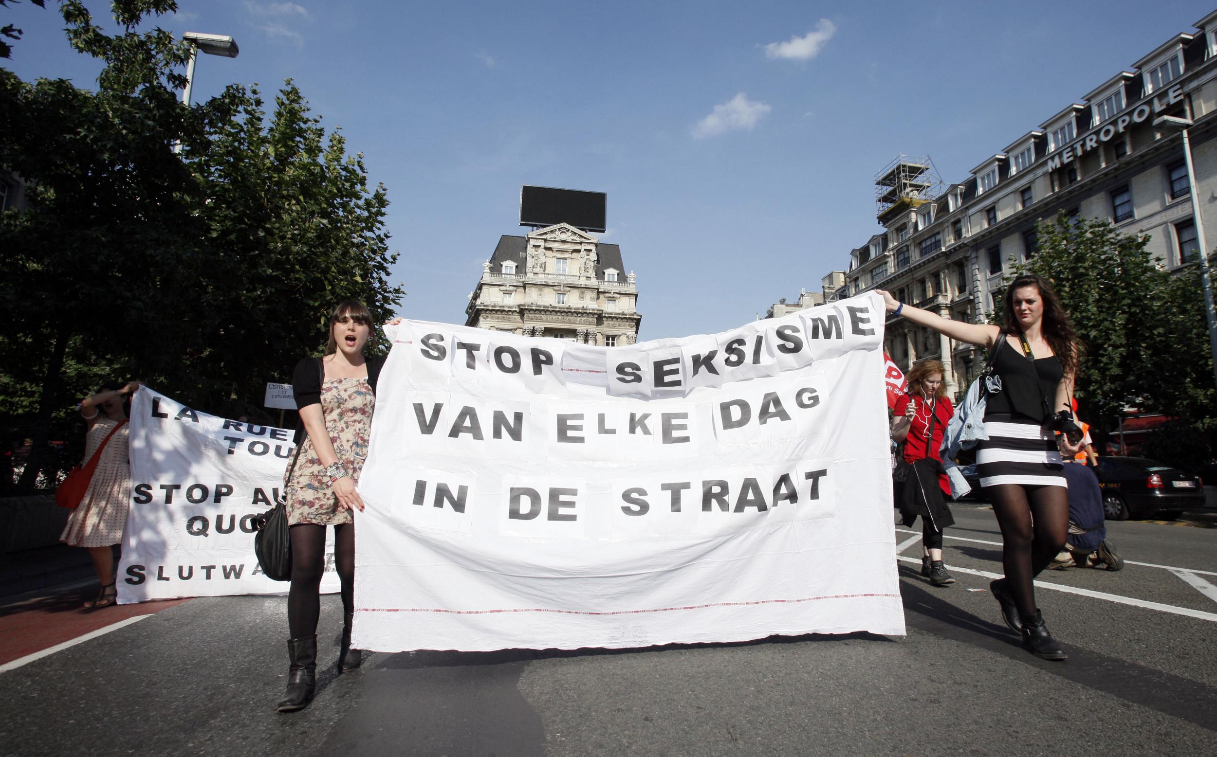 Women in Belgium hold up a sign that reads "Stop everyday sexism in the streets" before the new law was passed