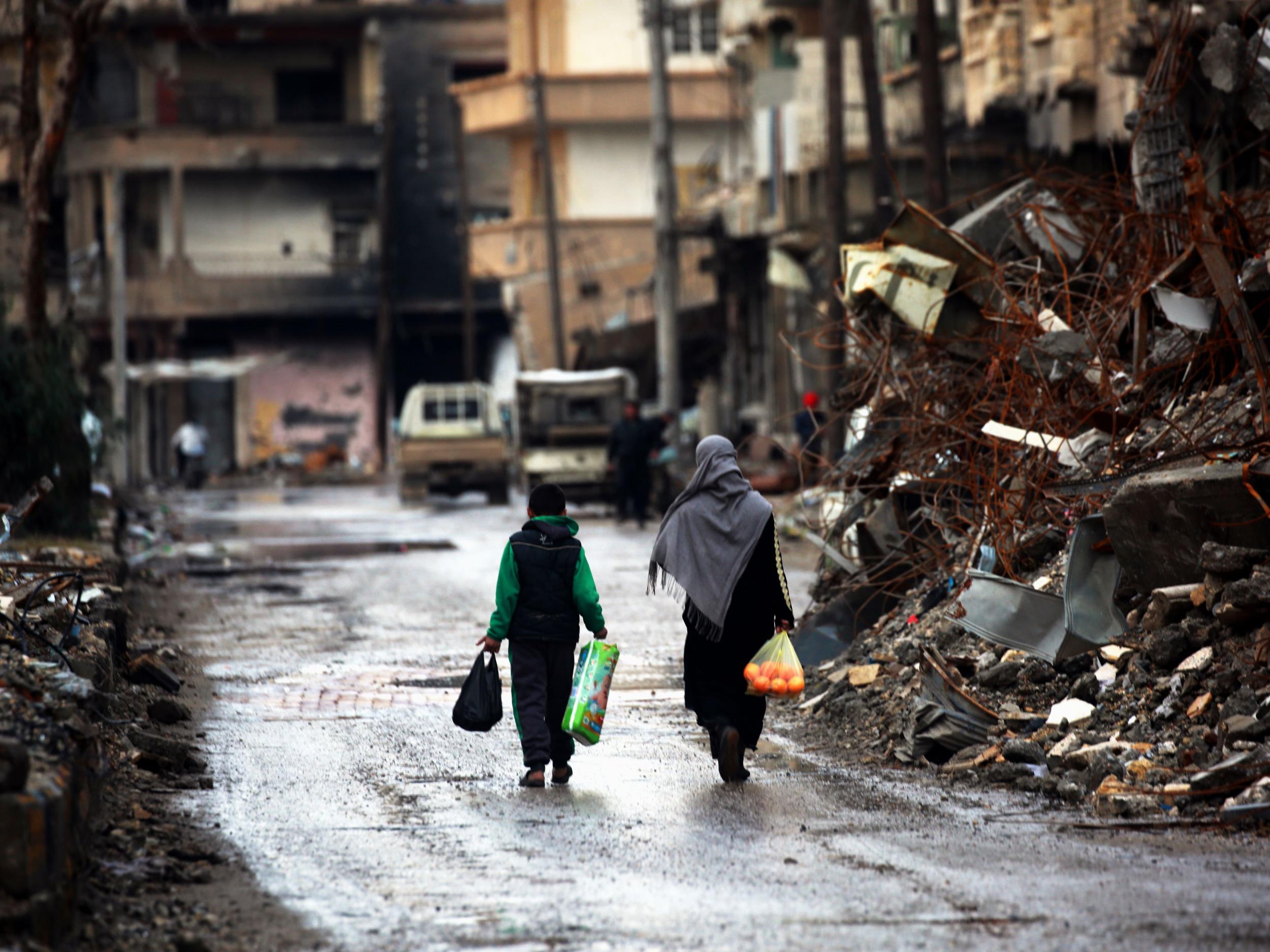 Syrians walk along a destroyed street in Raqqa. Officials estimate 150,000 people have returned to the city after the liberation – around half its pre-war population. But evidence of them is scant on the streets (Getty)