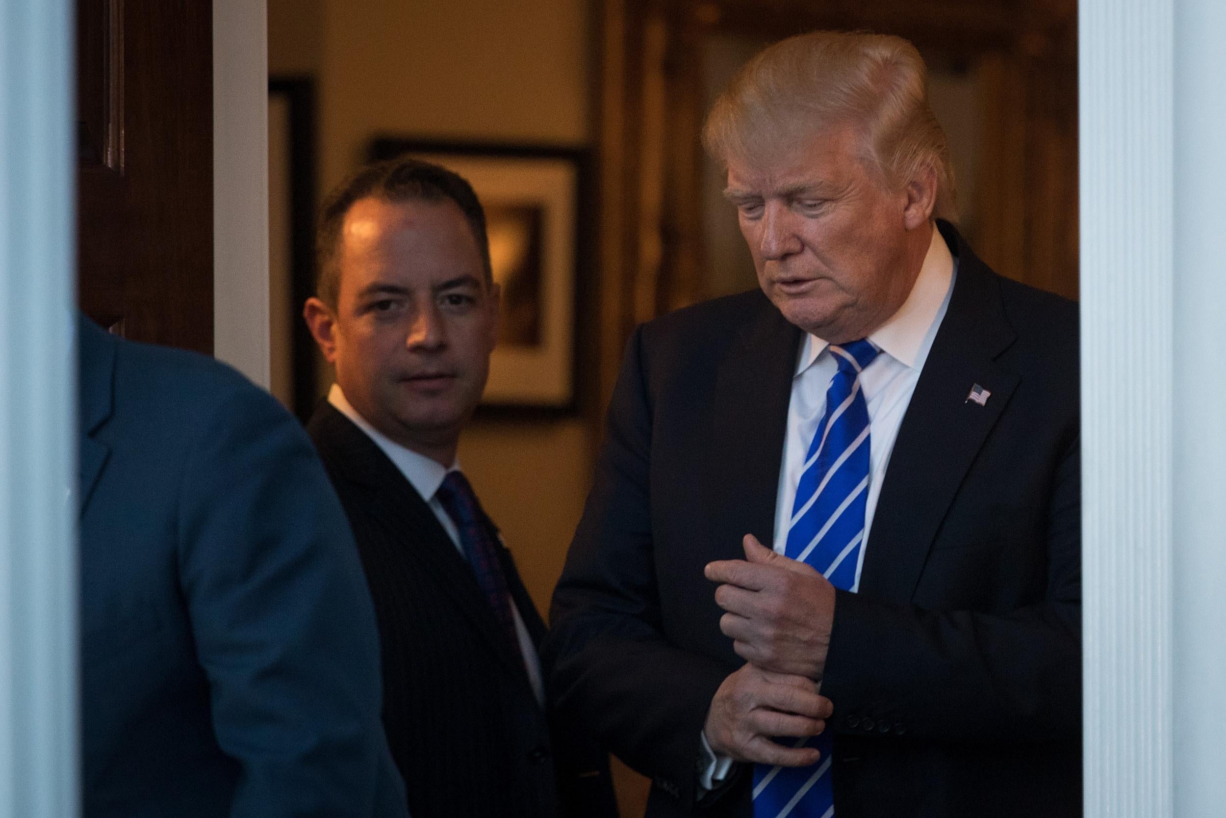 Reince Priebus looks on as President-elect Donald Trump prepares to greet Bob Woodson, president of the Center for Neighborhood Enterprise