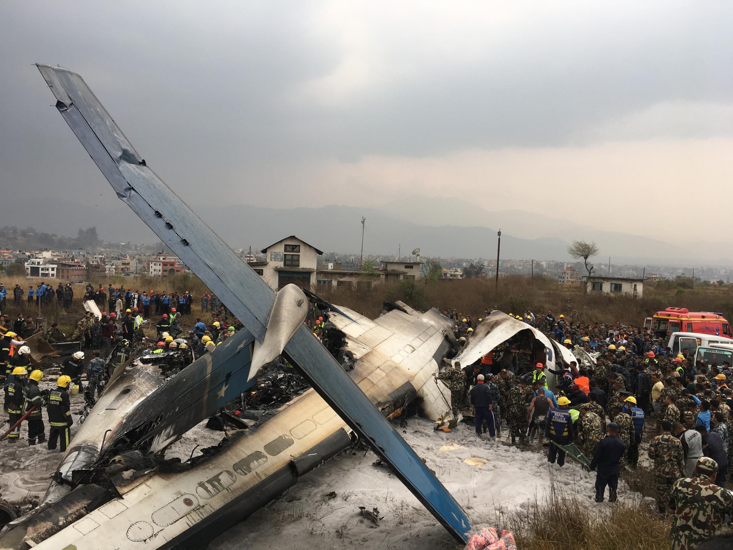 Nepalese rescuers work to rescue passengers from a plane arriving from Bangladesh that crashed at the airport in Kathmandu, Nepal