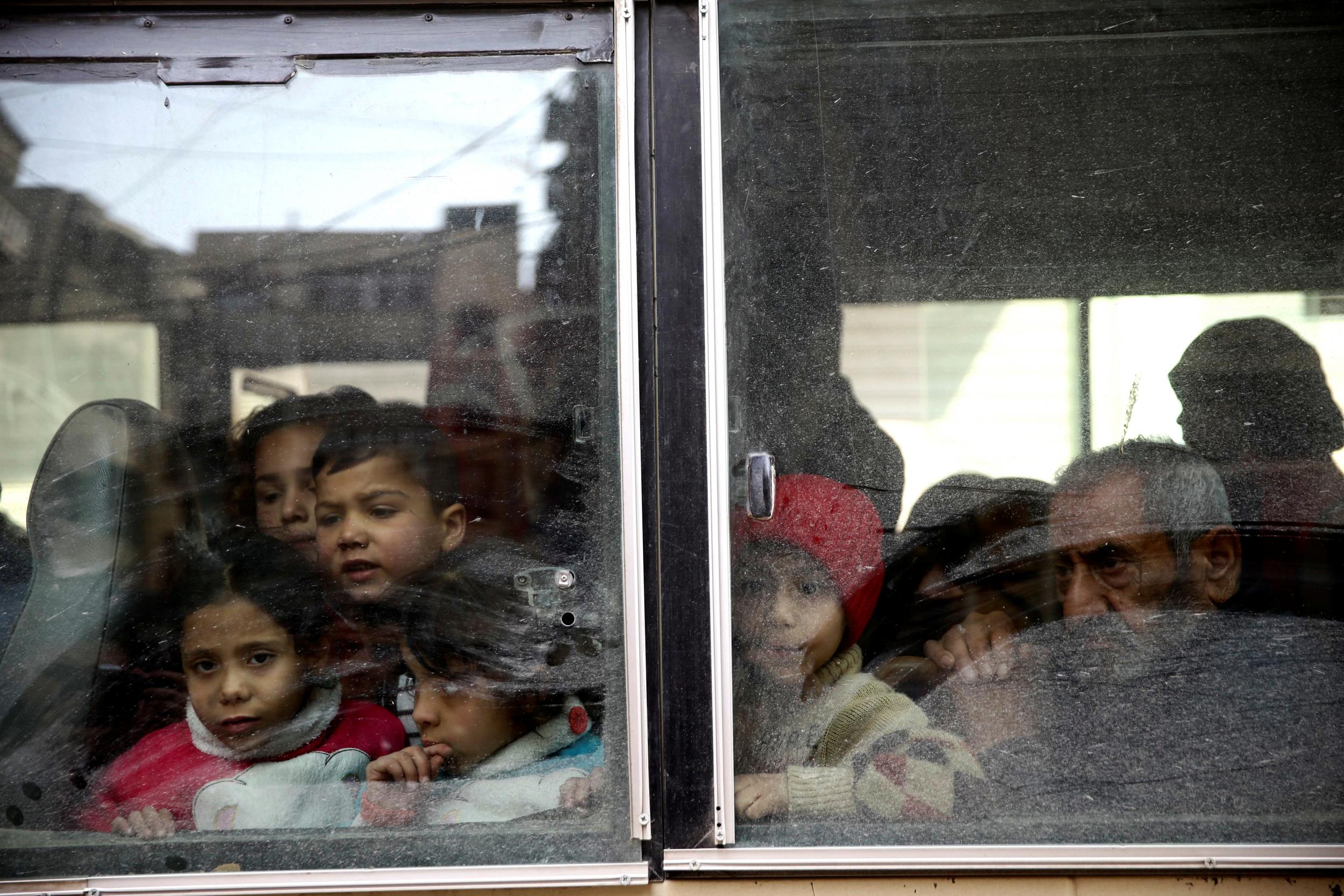 Children look through a bus window during a medical evacuation from the besieged town of Douma in Eastern Ghouta on 13 March 2018