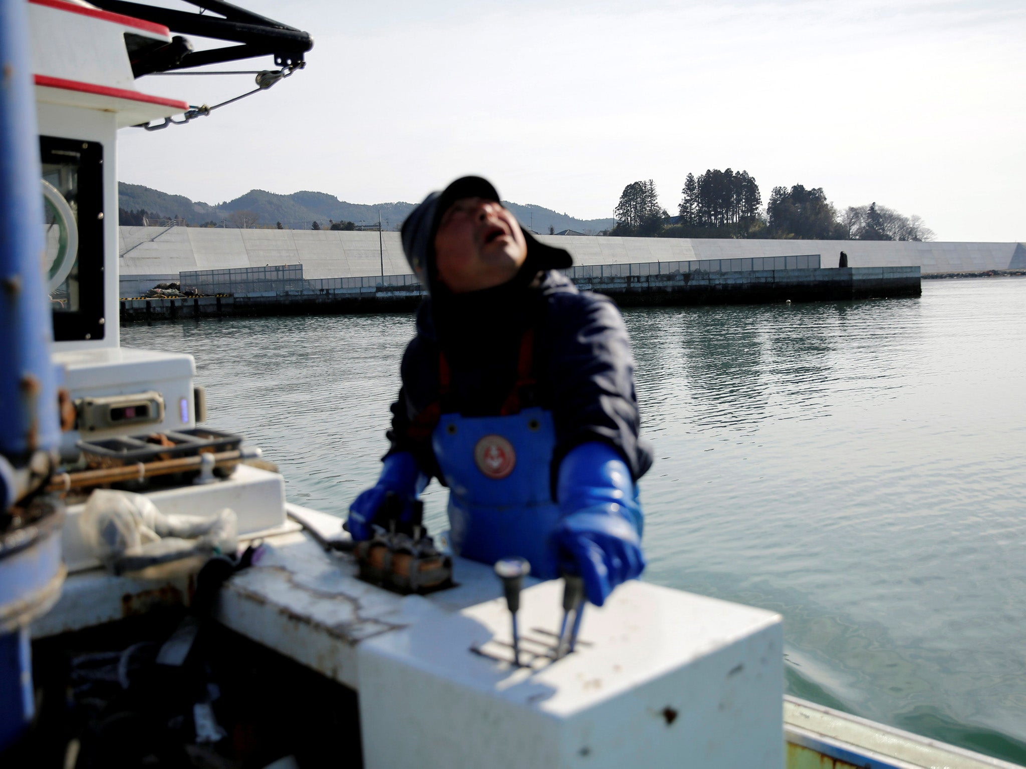 Atsushi Fujita sails his boat as he leaves a dock where sea walls are installed, at Hirota Bay in Rikuzentakata