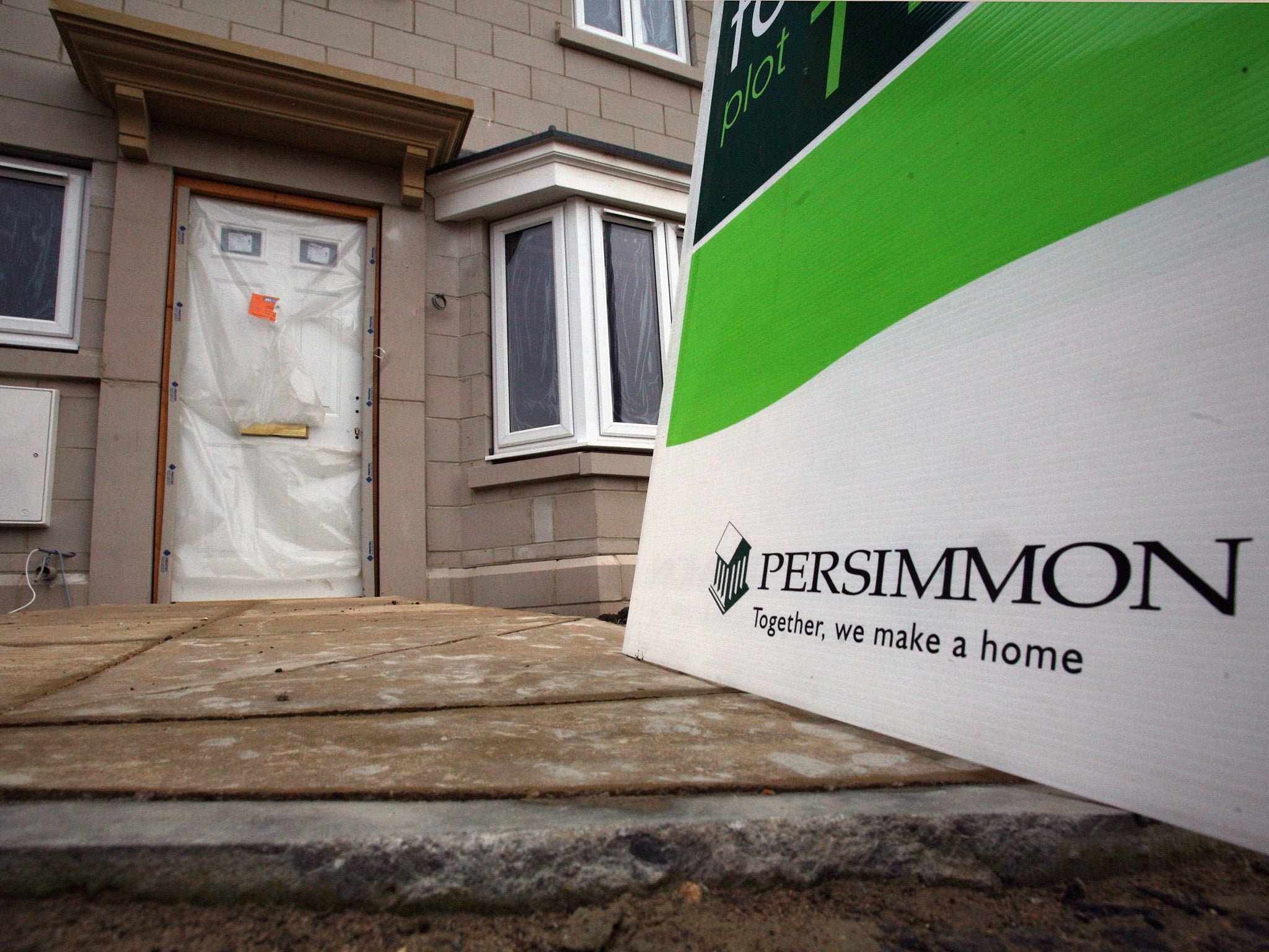 A 'for sale' sign is displayed outside a new build house on a housing estate by developer and housebuilder Persimmon