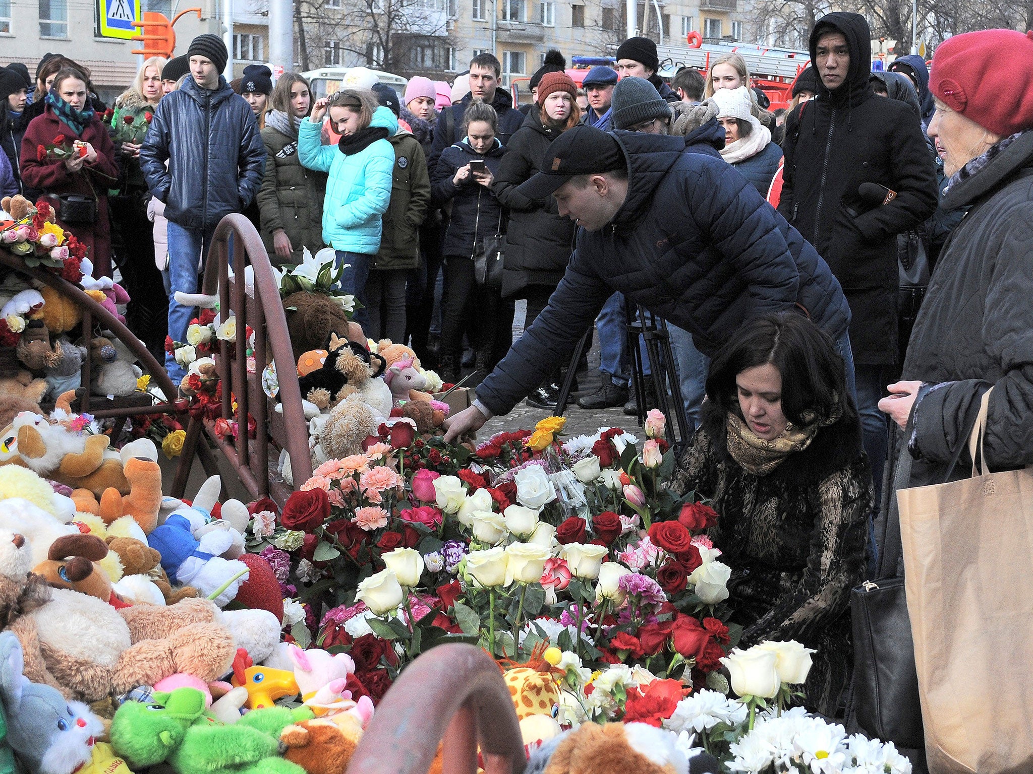 People place toys and flowers at a makeshift memorial for the victims of a shopping mall fire in Kemerovo