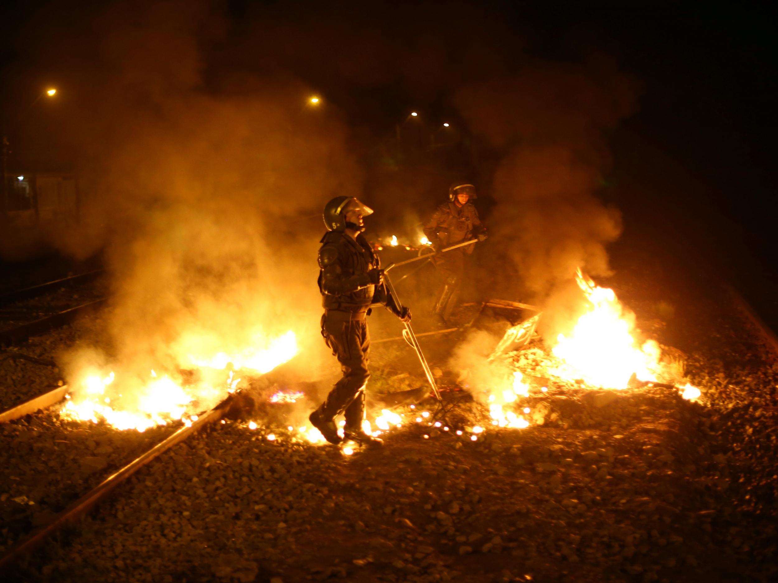 Riot police remove barricades from train tracks which are used to transport rubbish