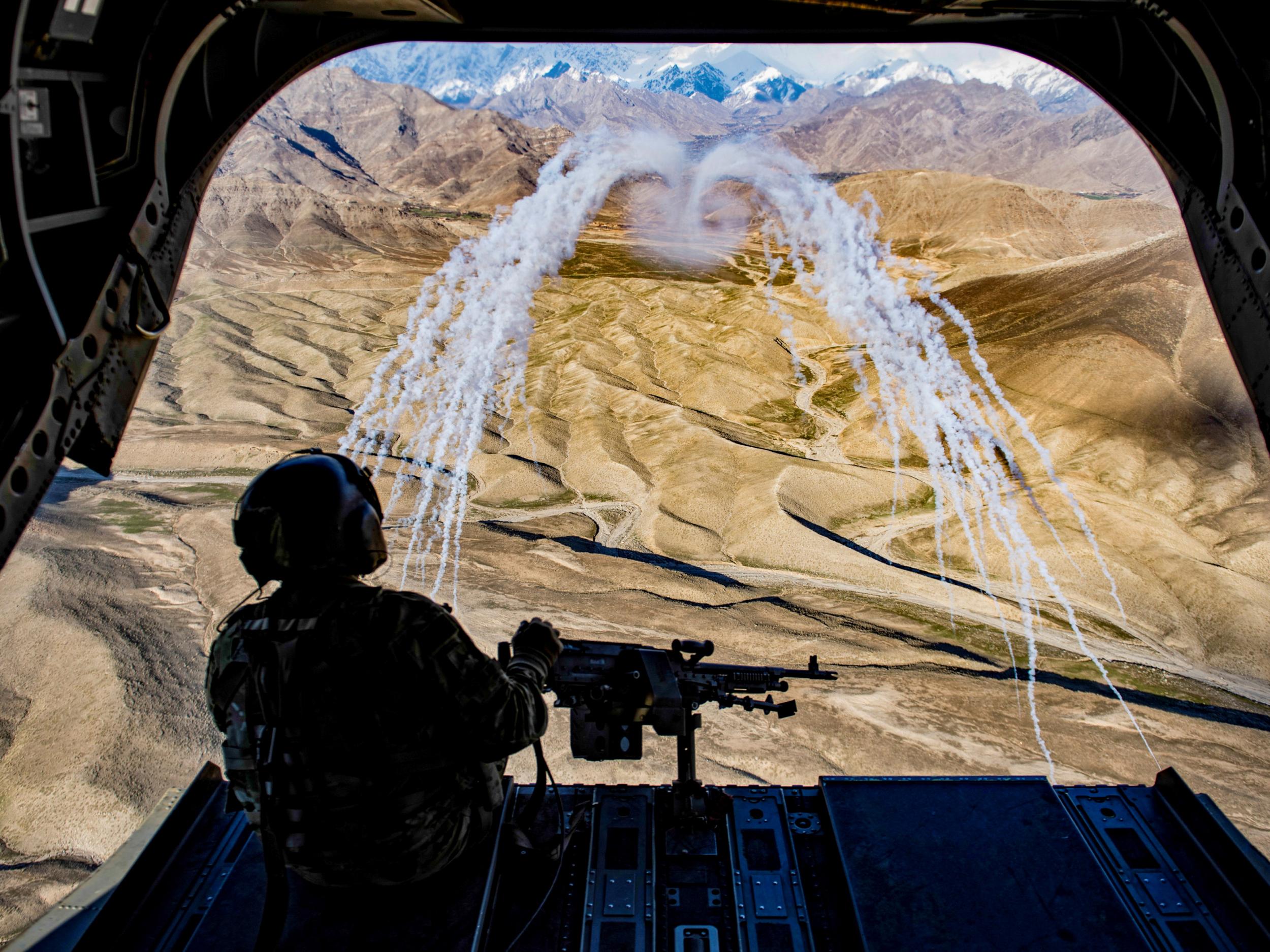 A US army crew chief, on board a CH-47F Chinook helicopter, observes the successful test of flares during a training flight in Afghanistan