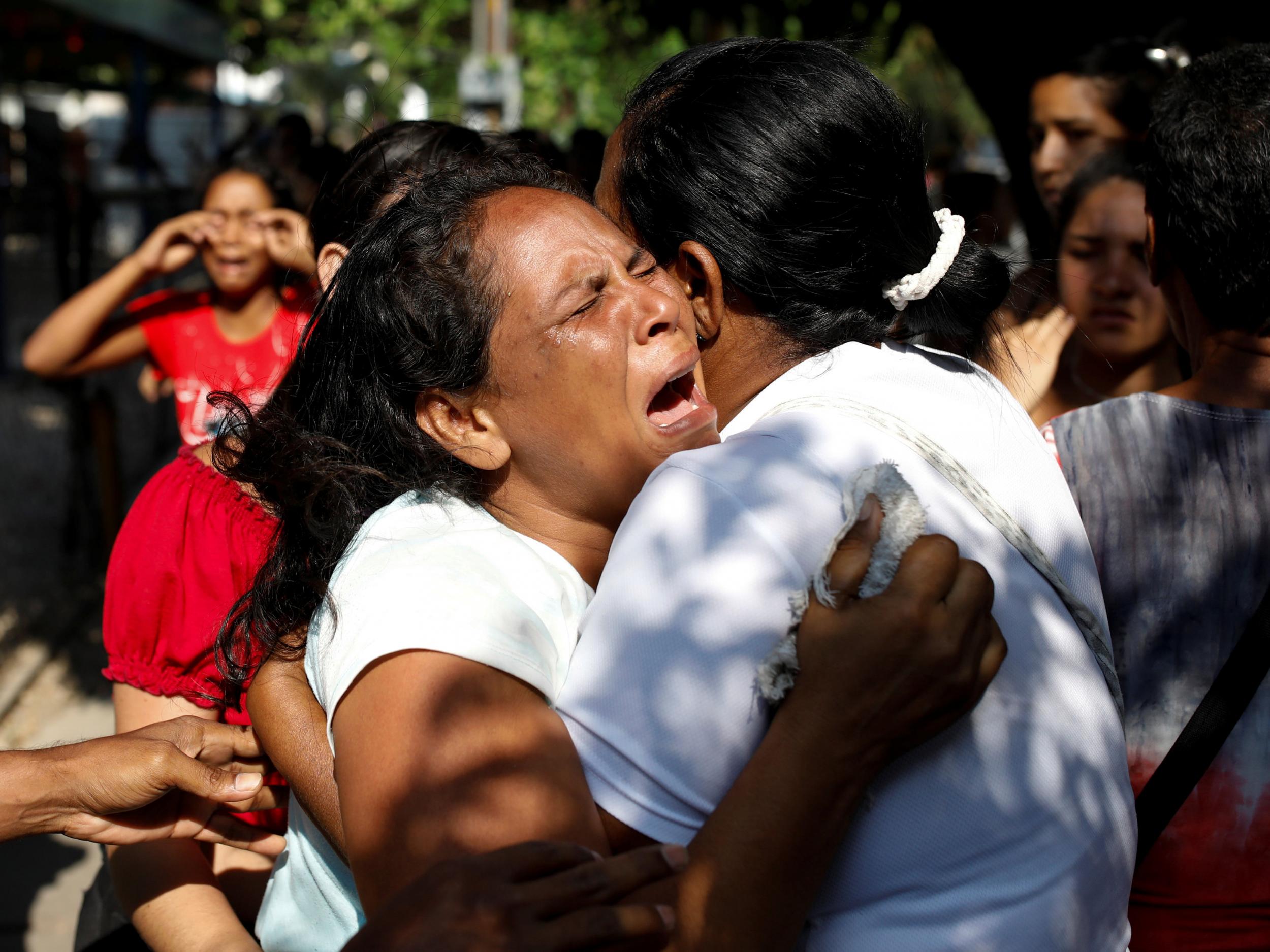 Relatives of inmates held at the General Command of the Carabobo Police react as they wait outside the prison