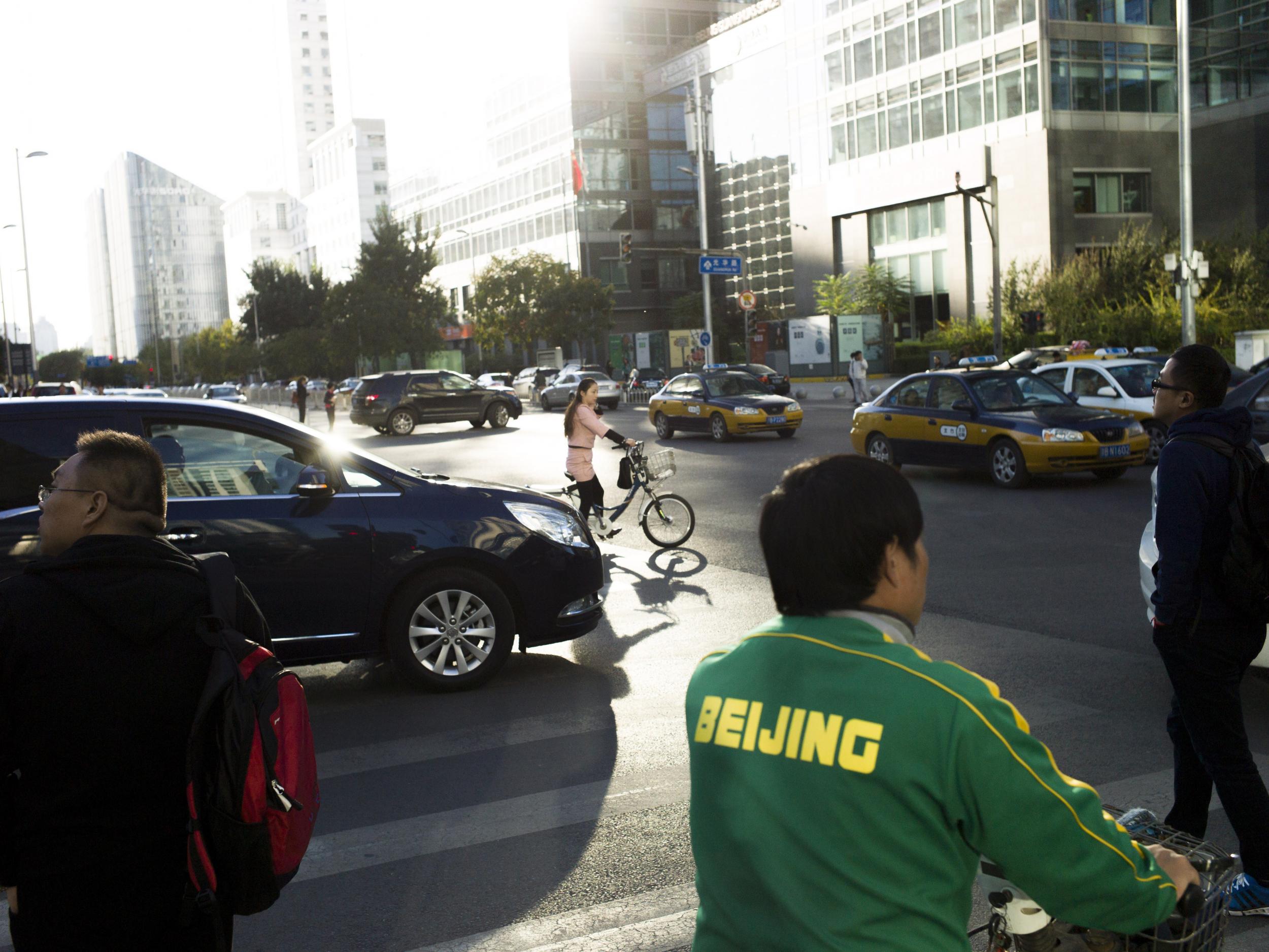 People wait at a road crossing in the central business district of Beijing