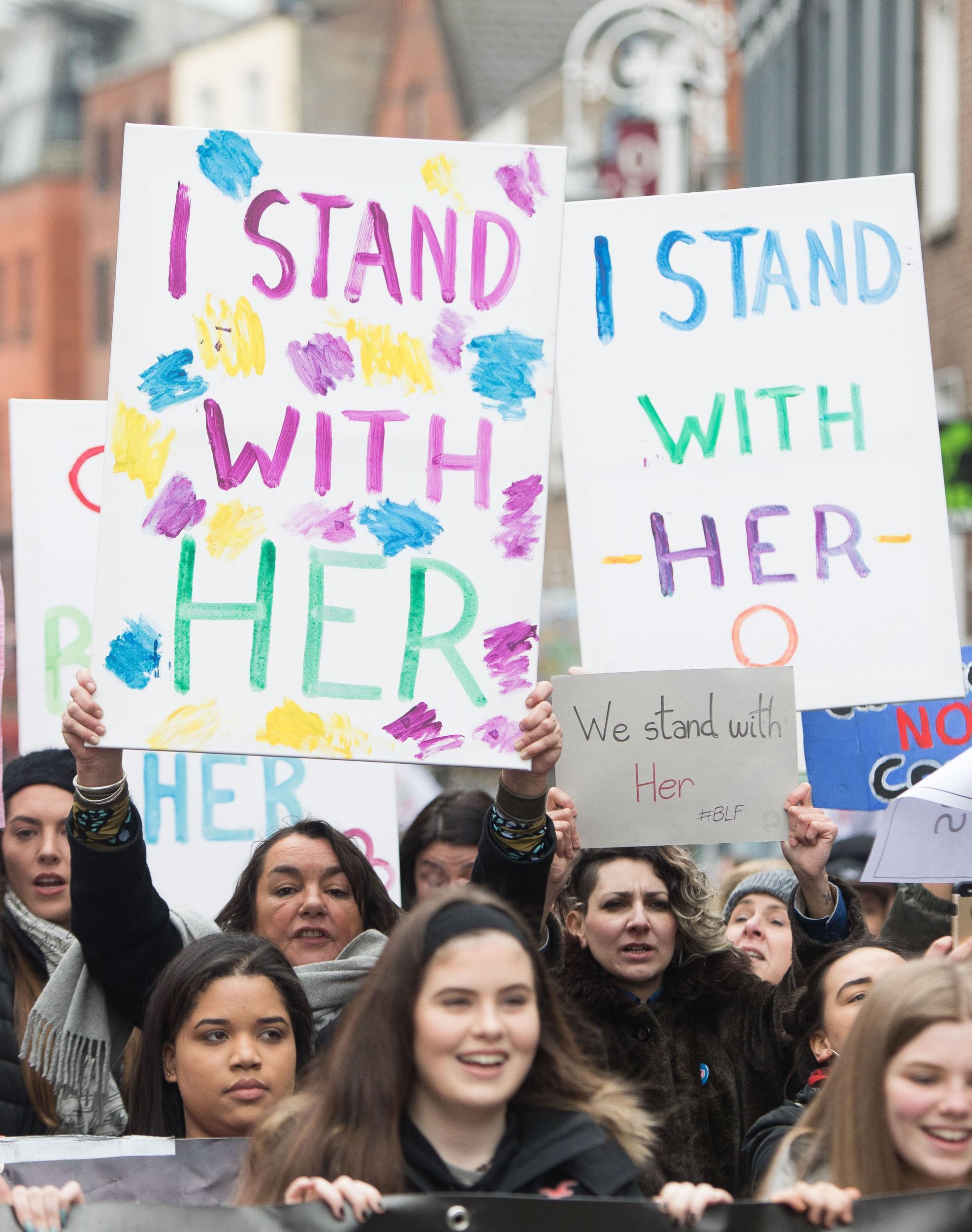 Colourful banners read ‘I stand with her’ – meaning the complainant