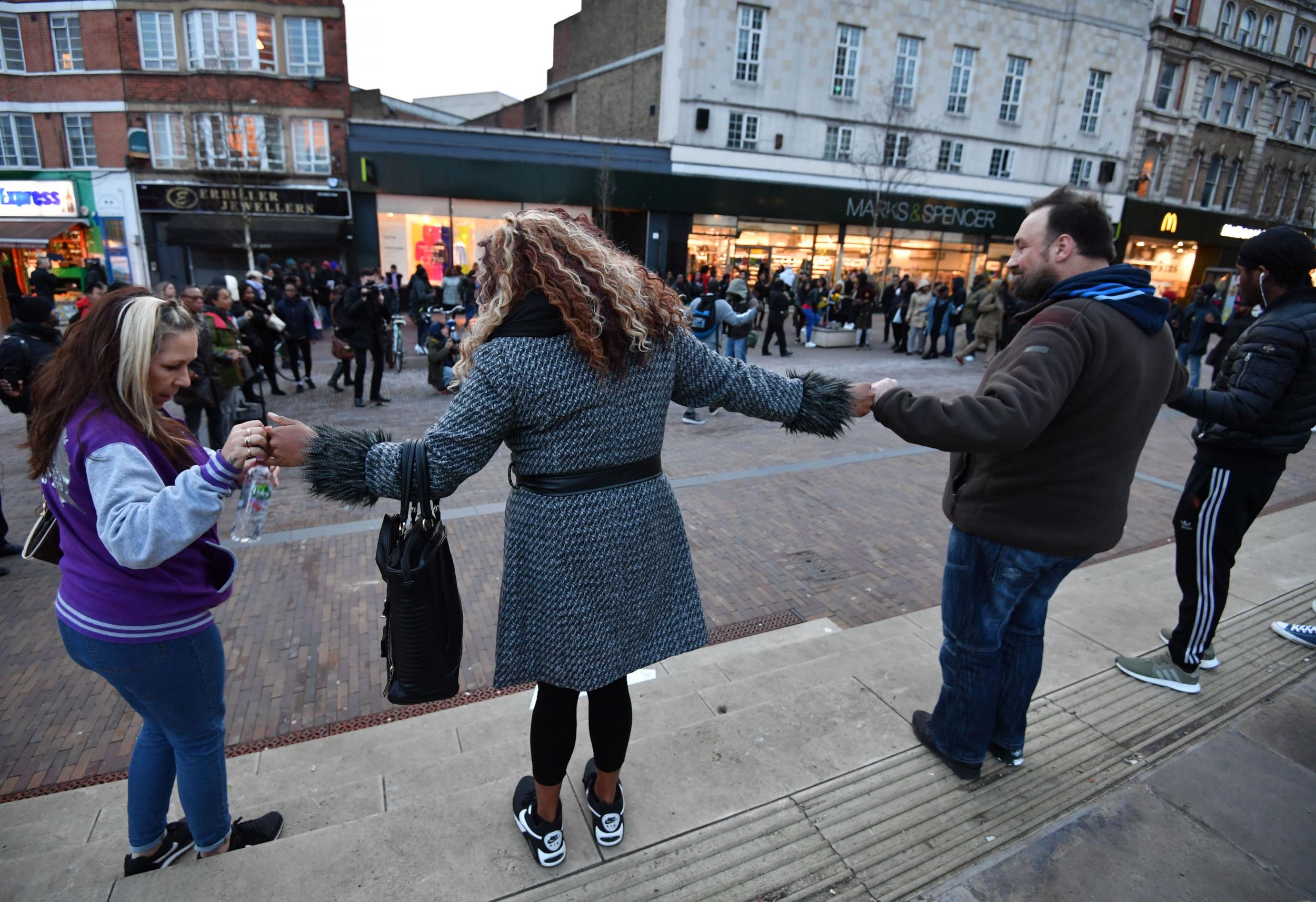 Demonstrators link hands during a protest against violent crime outside Hackney Central station