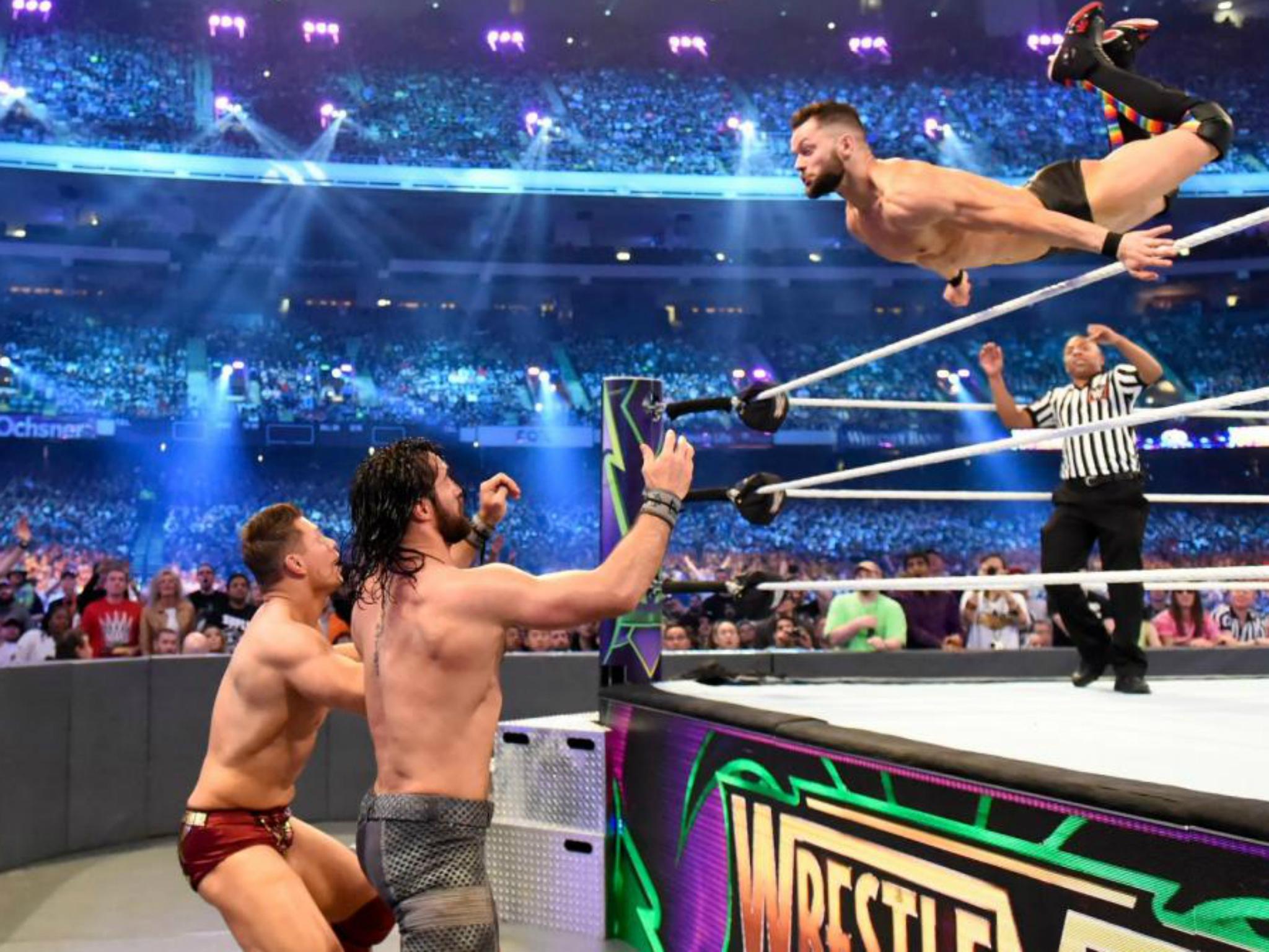 Finn Balor soars over the top rope to splash onto Rollins and The Miz