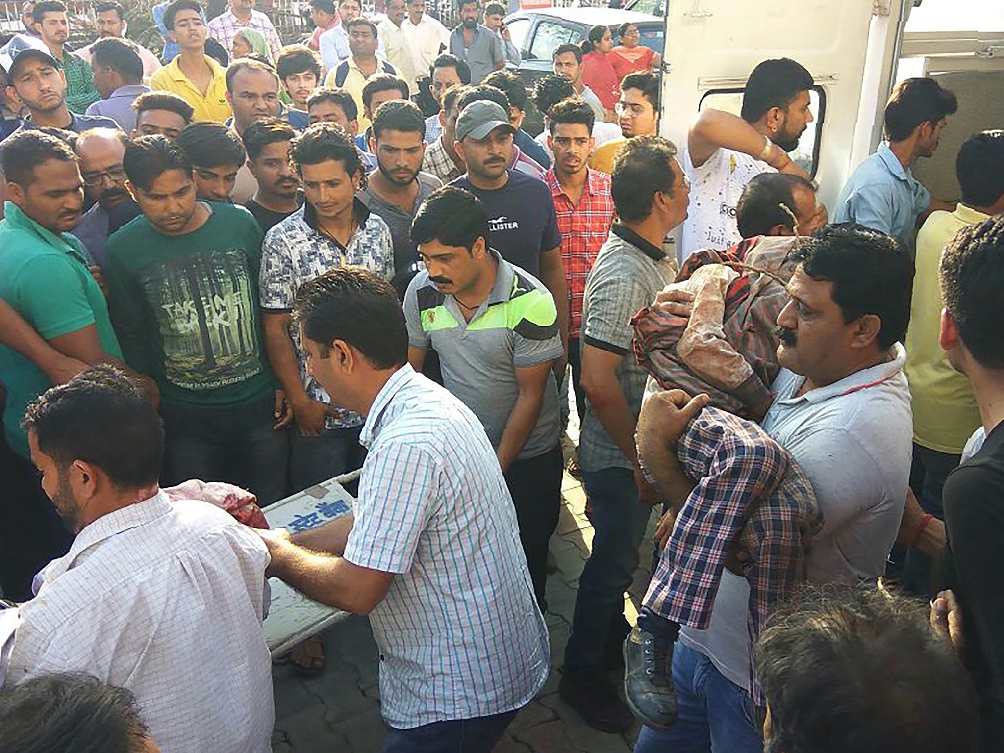 People carry injured survivors to hospital after a private school bus plunged off a cliff in Nurpur, Kangra district