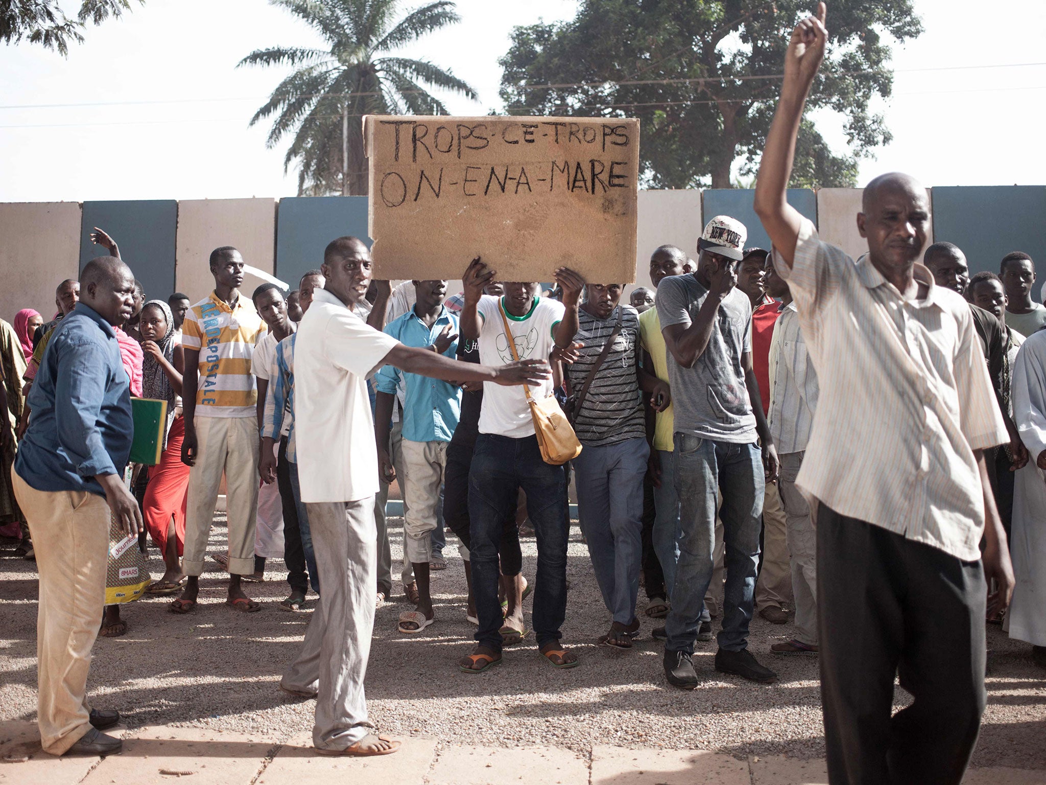 A demonstrator holds up a placard reading ‘Too much is too much, we have enough’ (Getty)