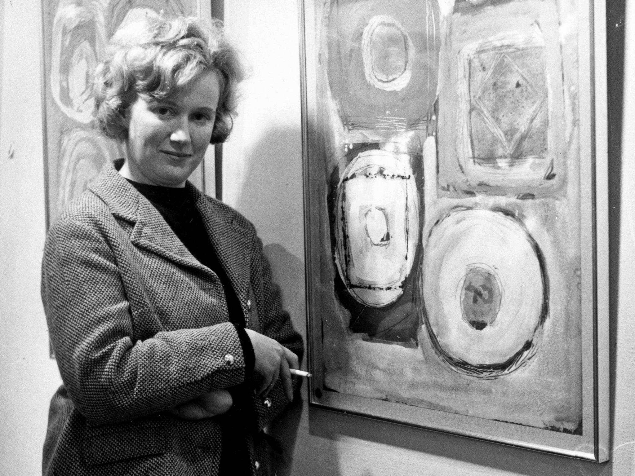 Ayres smokes a trademark Player’s Navy Cut cigarette as she poses with one of her paintings at a 1962 exhibition of her work in London