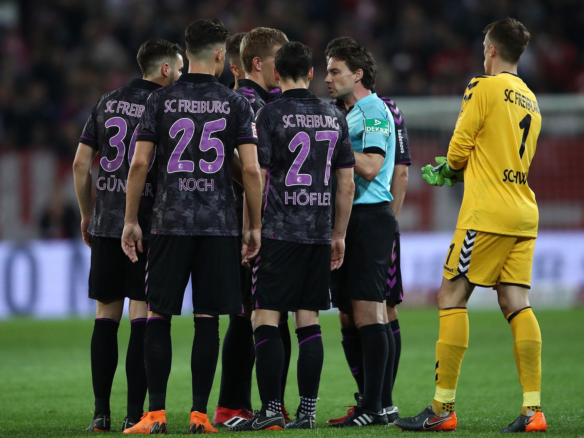 Referee Guido Winkmann is confronted after ordering the players back onto the pitch