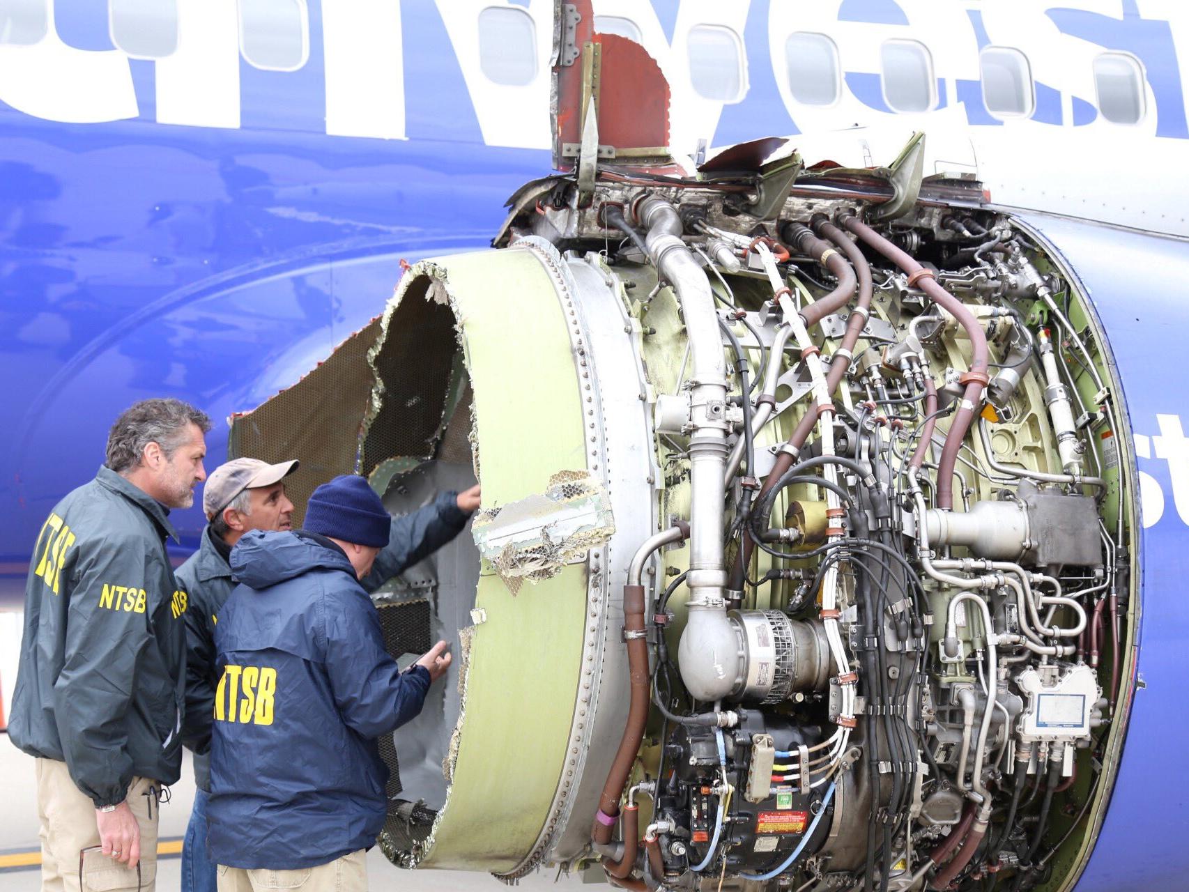 National Transportation Safety Board investigators examine damage to the engine of the Southwest Airlines plane